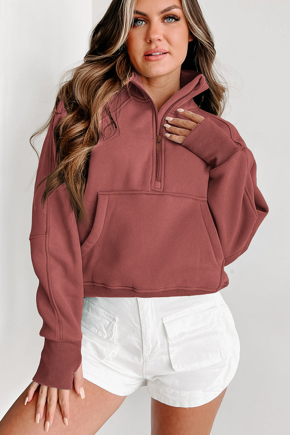 Brown zip-up sweatshirt with stand collar and thumbhole sleeves, featuring a textured design and kangaroo pocket.