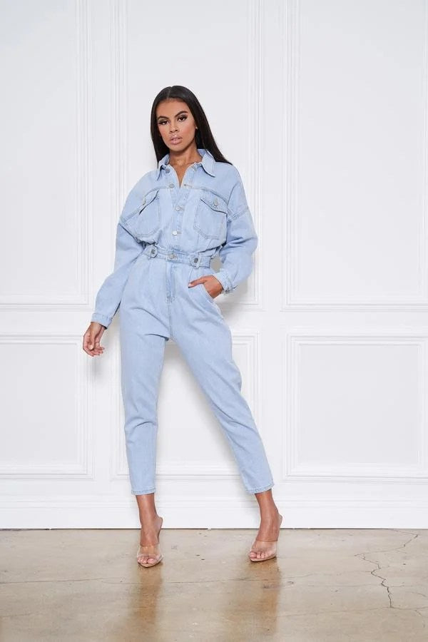 Light blue denim jumpsuit with button front and pockets, featuring long sleeves and a stylish design.