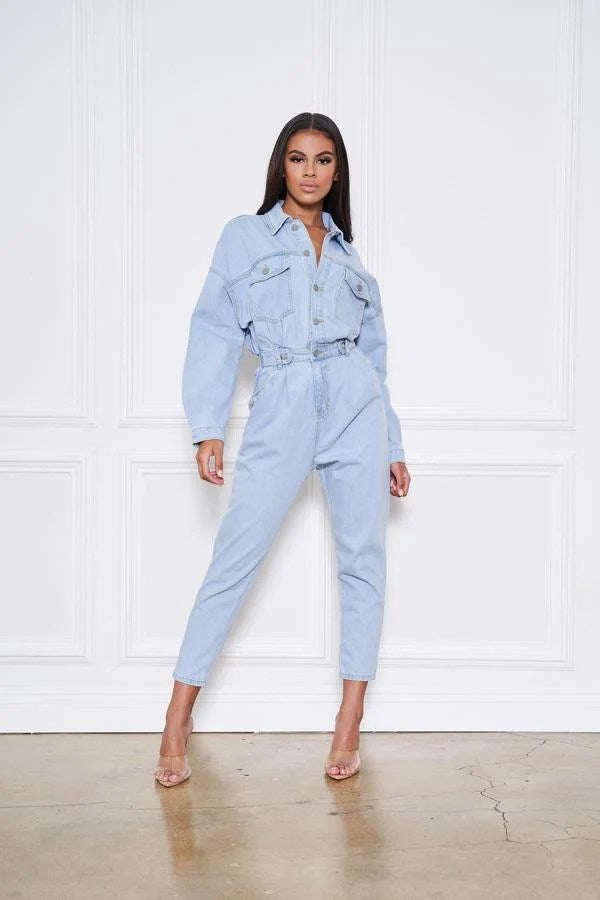 Light blue denim jumpsuit with button front and pockets, featuring long sleeves and a stylish design.
