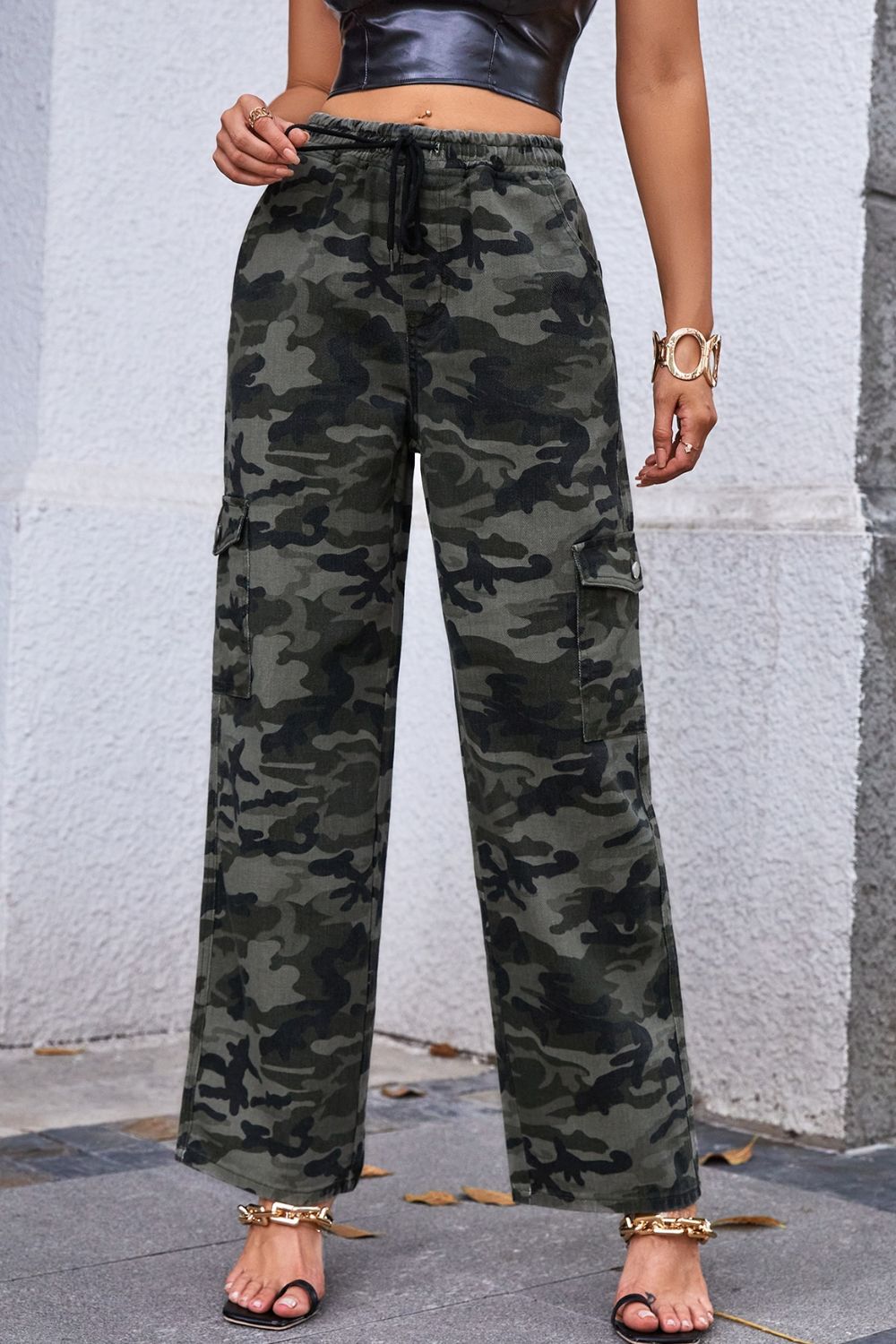 A pair of stylish camouflage drawstring waist cargo pants displayed in a studio setting, showcasing multiple pockets and a casual design.