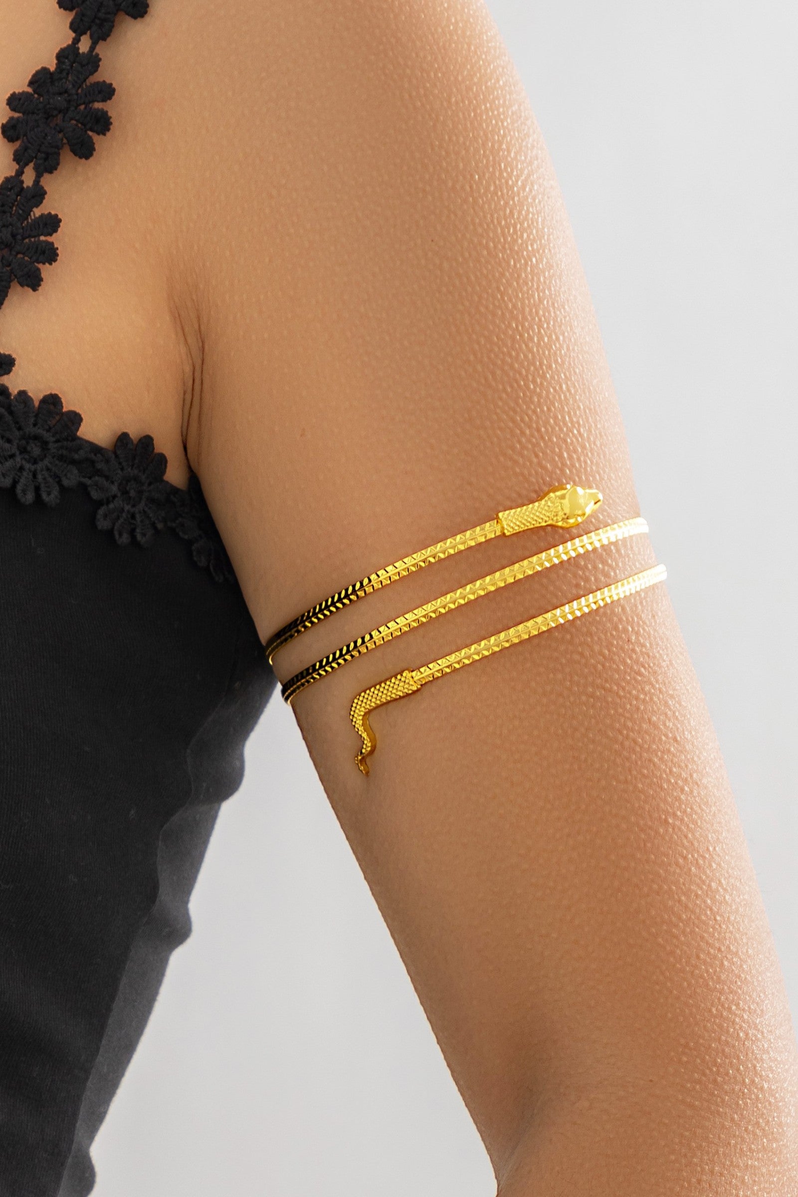 Gold upper arm chain designed in the shape of a snake, showcasing intricate detailing and a luxurious finish.