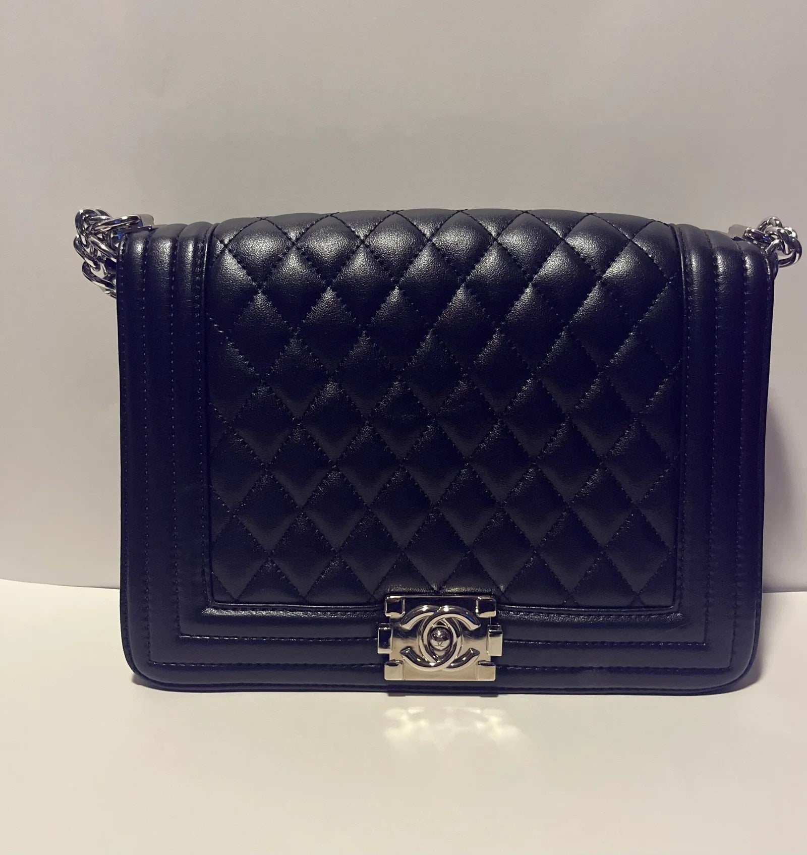 Charming shoulder bag with gold handle chain, featuring quilted design and silver-tone hardware.