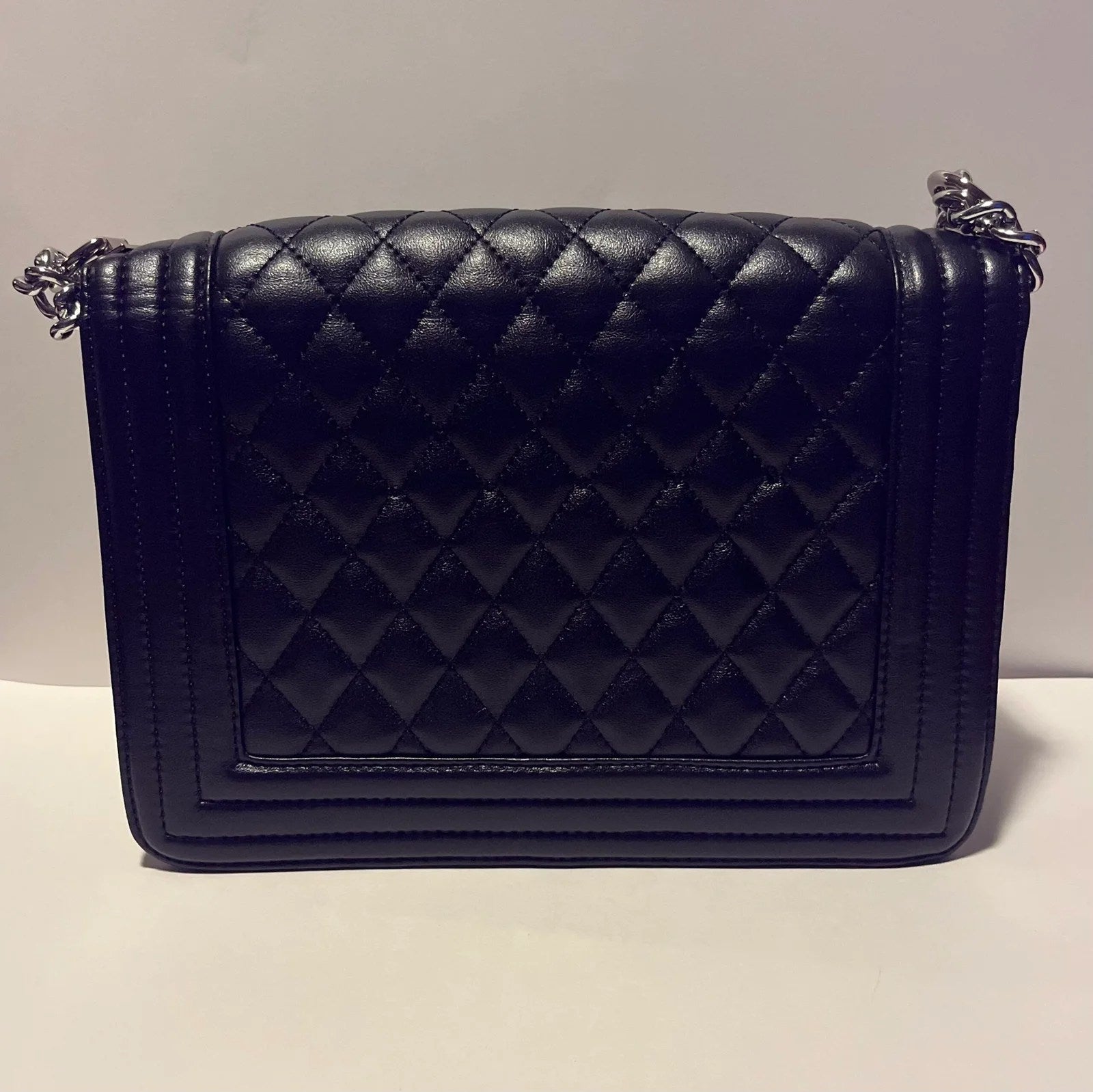 Charming shoulder bag with gold handle chain, featuring quilted design and silver-tone hardware.