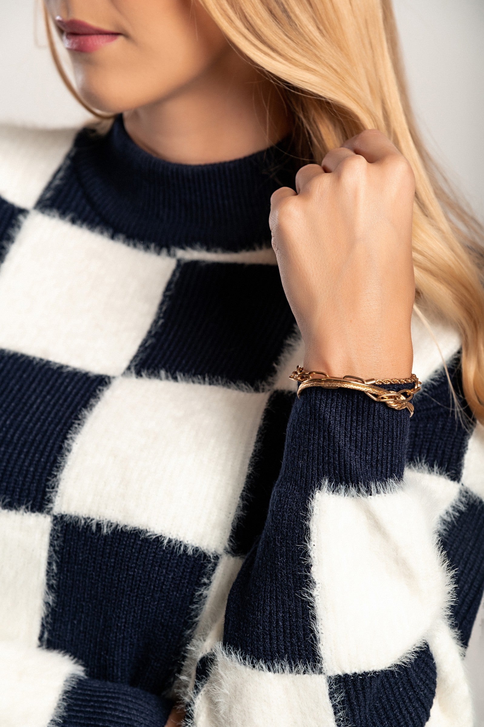 Checkerboard print sweater in blue and white, featuring long sleeves and a round neckline, made from soft fabric.