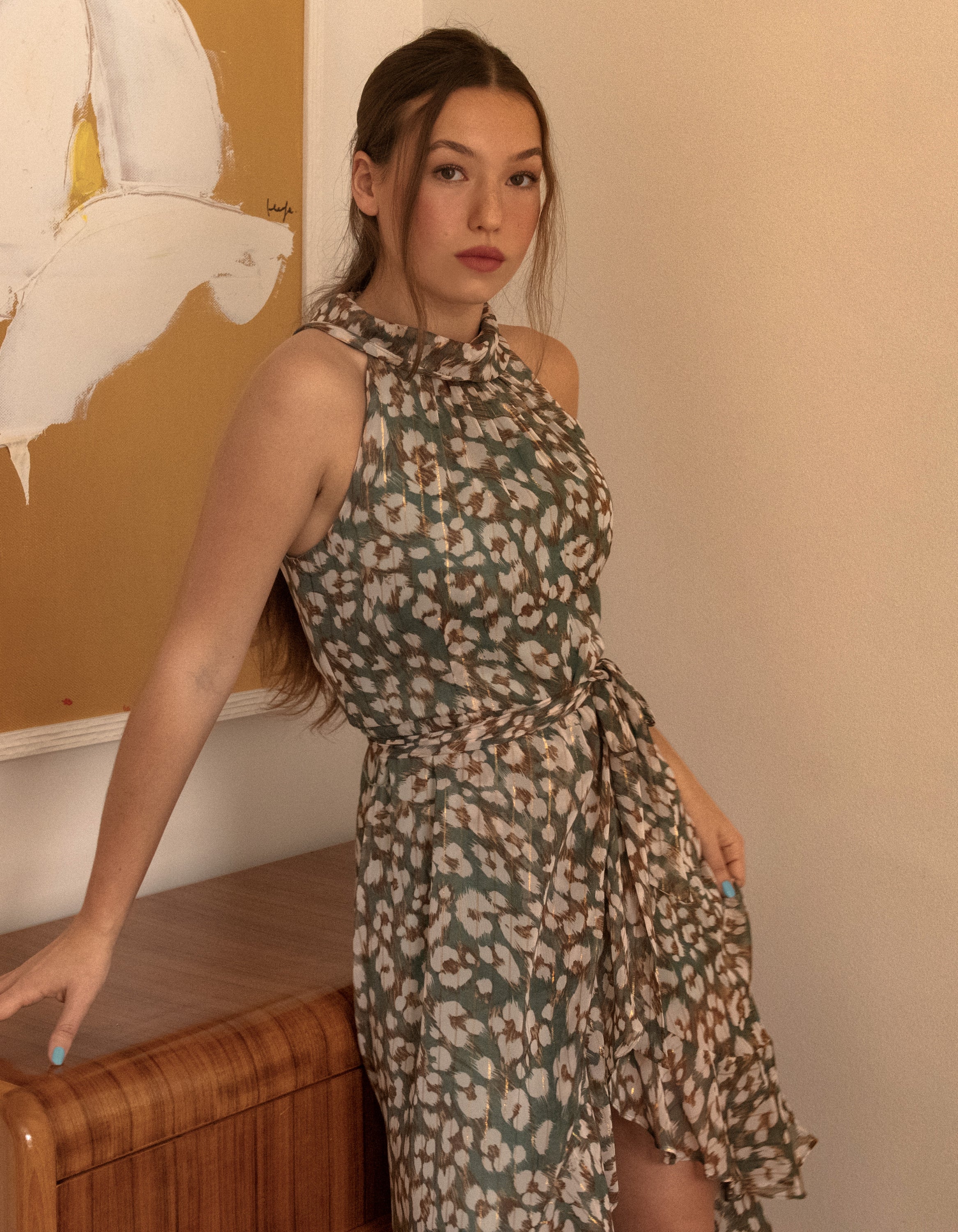 Clemence Midi Dress featuring an asymmetrical faux wrap design, high halter neckline, and wildflower print in sage green.