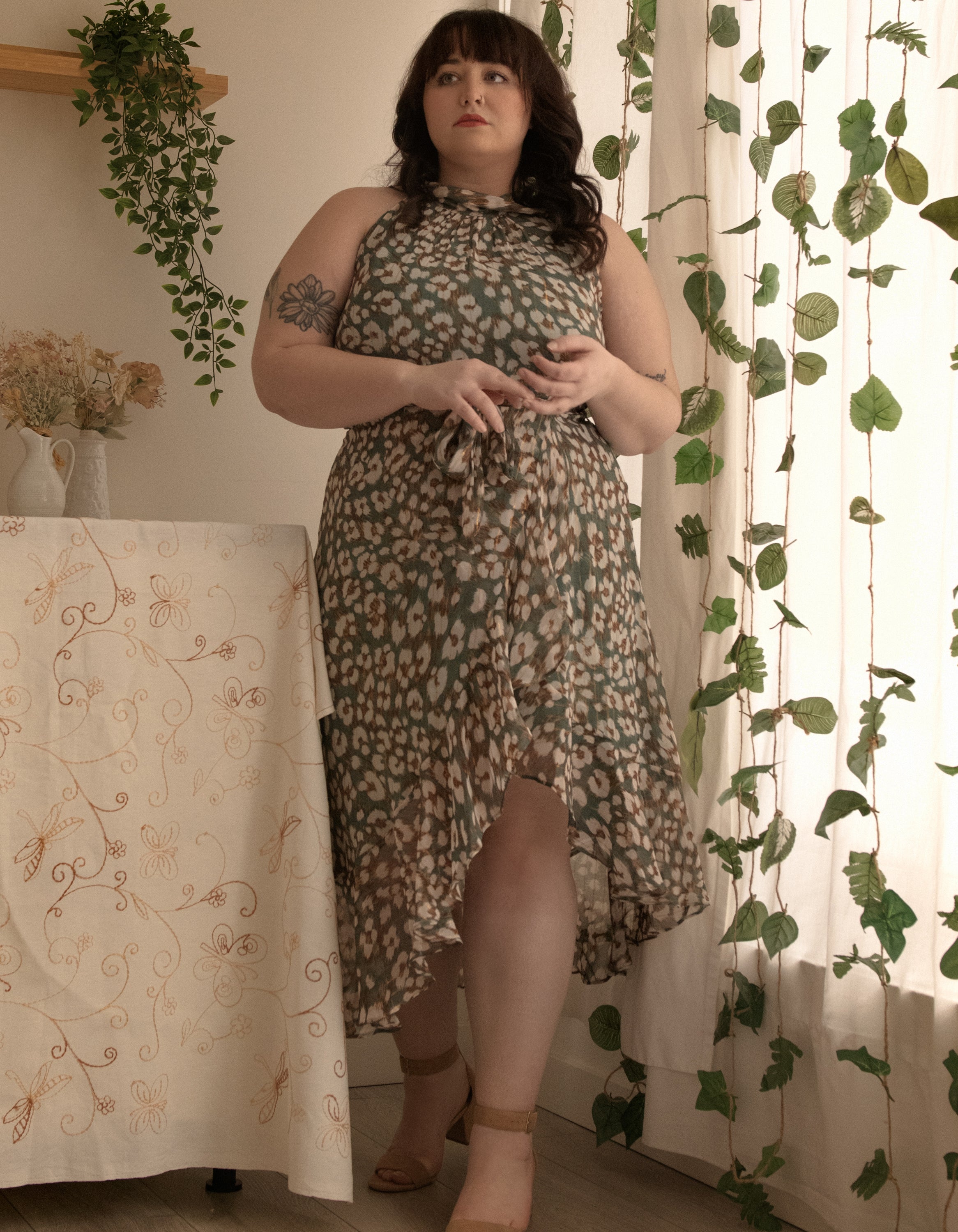 Clemence Midi Dress featuring an asymmetrical faux wrap design, high halter neckline, and wildflower print in sage green.