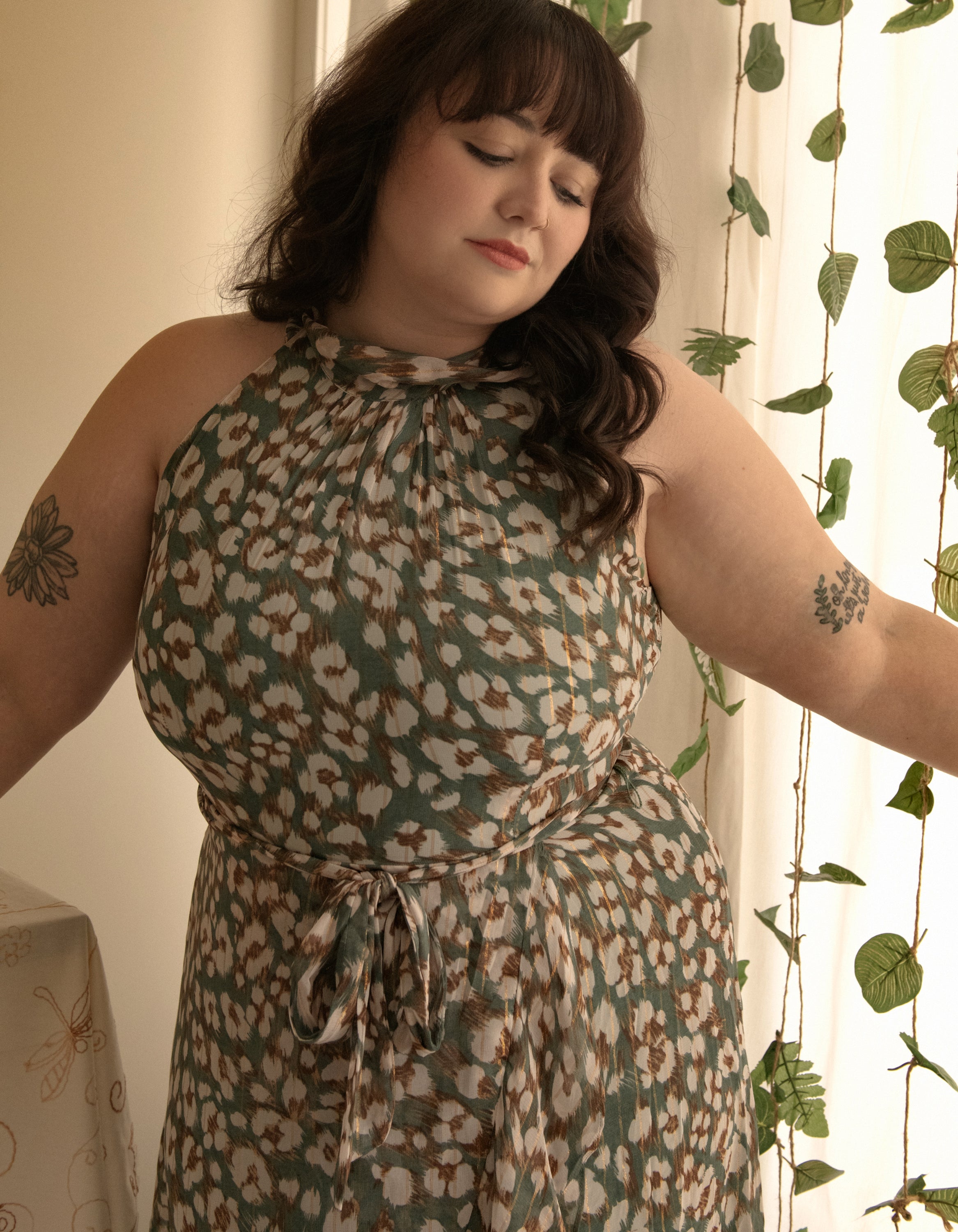 Clemence Midi Dress featuring an asymmetrical faux wrap design, high halter neckline, and wildflower print in sage green.