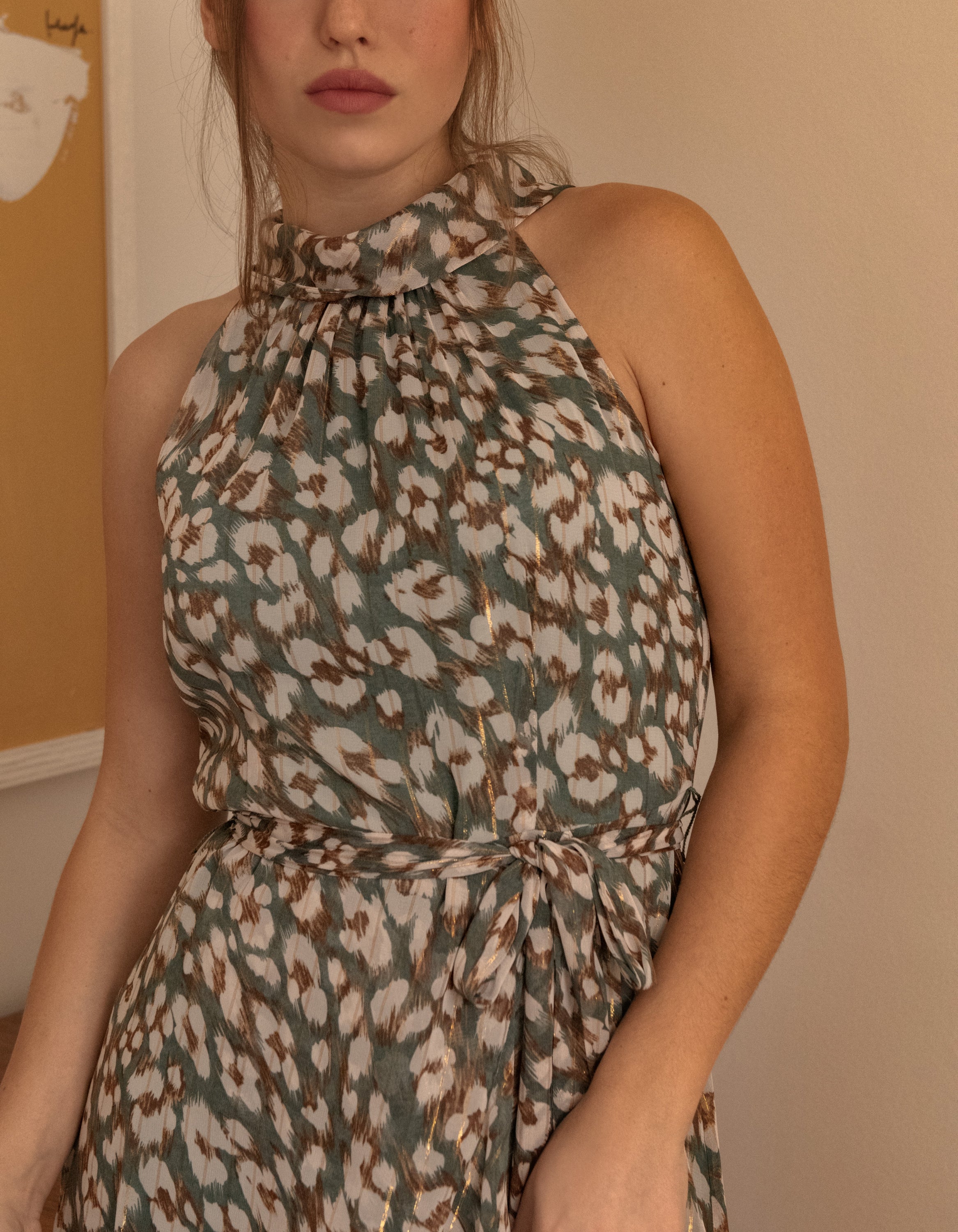 Clemence Midi Dress featuring an asymmetrical faux wrap design, high halter neckline, and wildflower print in sage green.