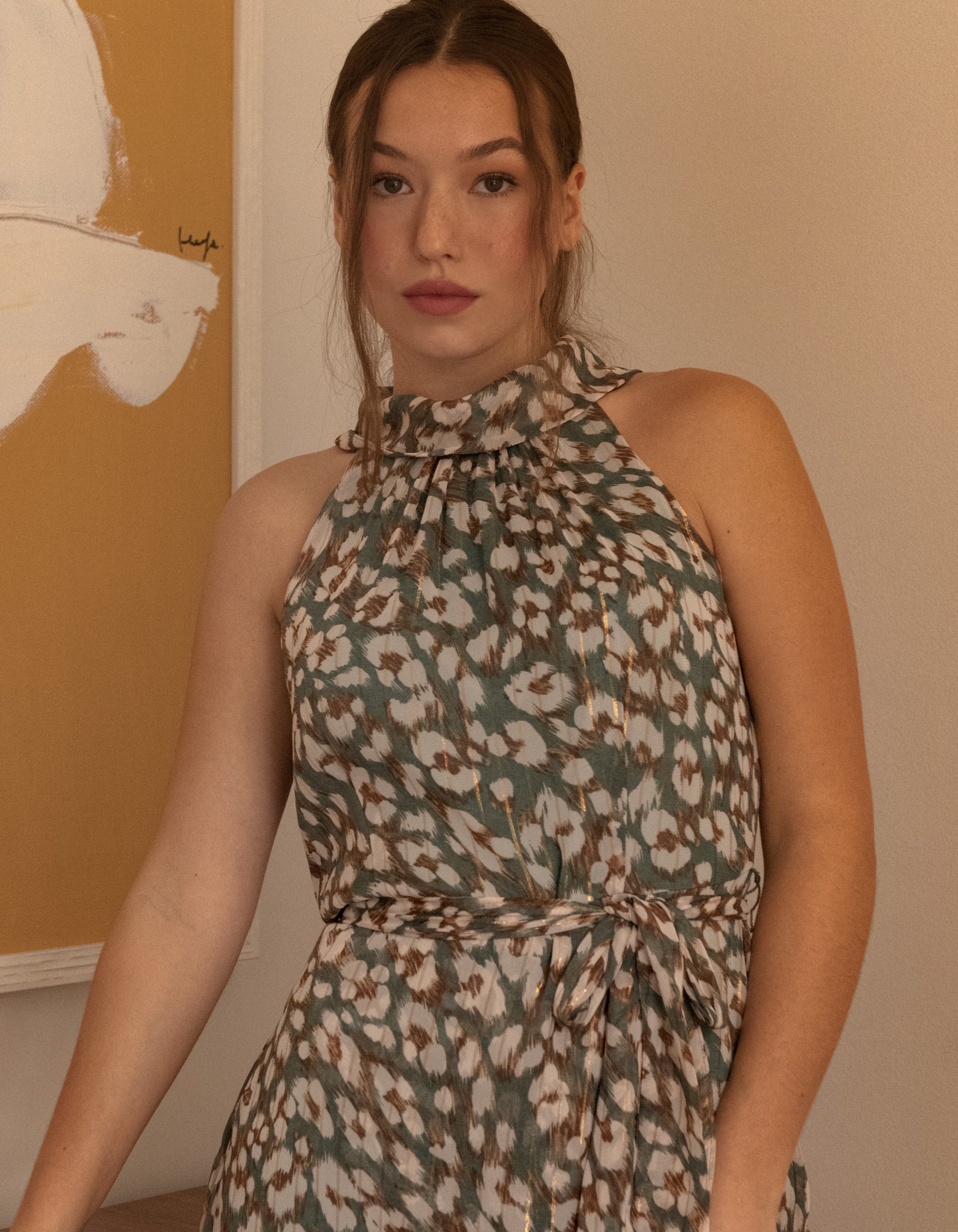 Clemence Midi Dress featuring an asymmetrical faux wrap design, high halter neckline, and wildflower print in sage green.