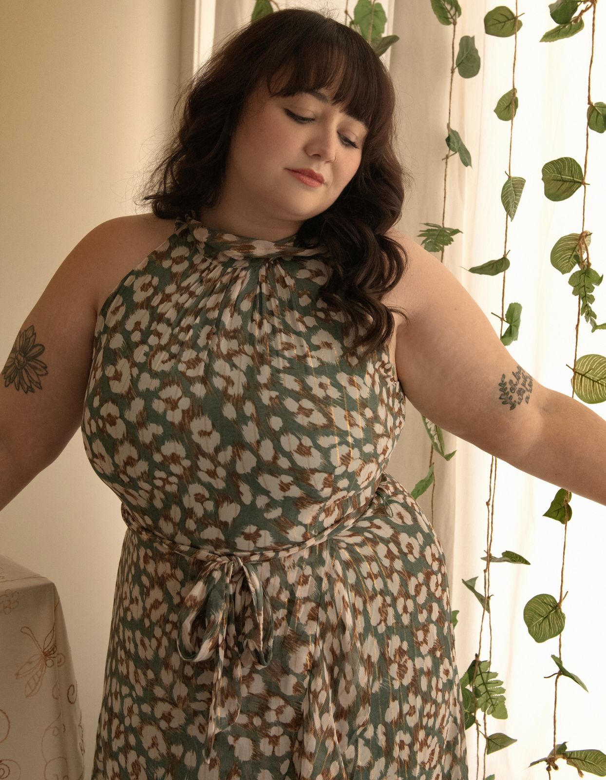 Clemence Midi Dress featuring an asymmetrical faux wrap design, high halter neckline, and wildflower print in sage green.