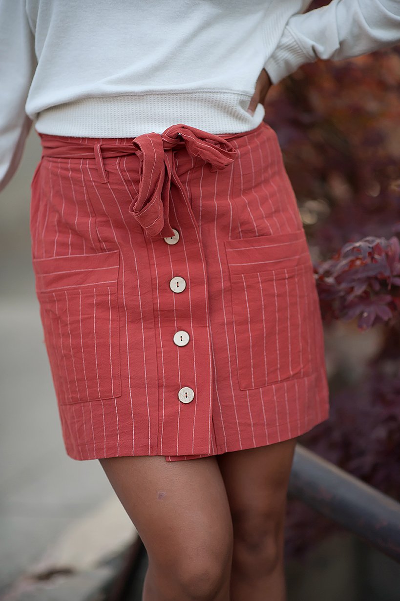 Coconut button stripe woven skirt in rust color with white stripes and a belt, featuring functional accent pockets.