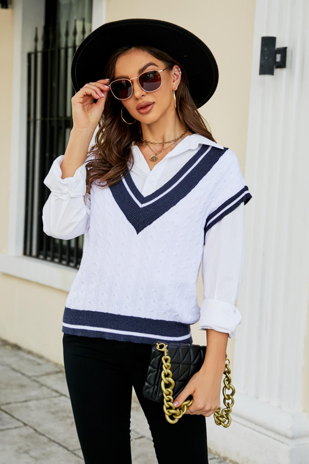A stylish Contrast V-Neck Cap Sleeve Sweater Vest displayed outdoors, featuring a chic design with a contrast pattern and cap sleeves.