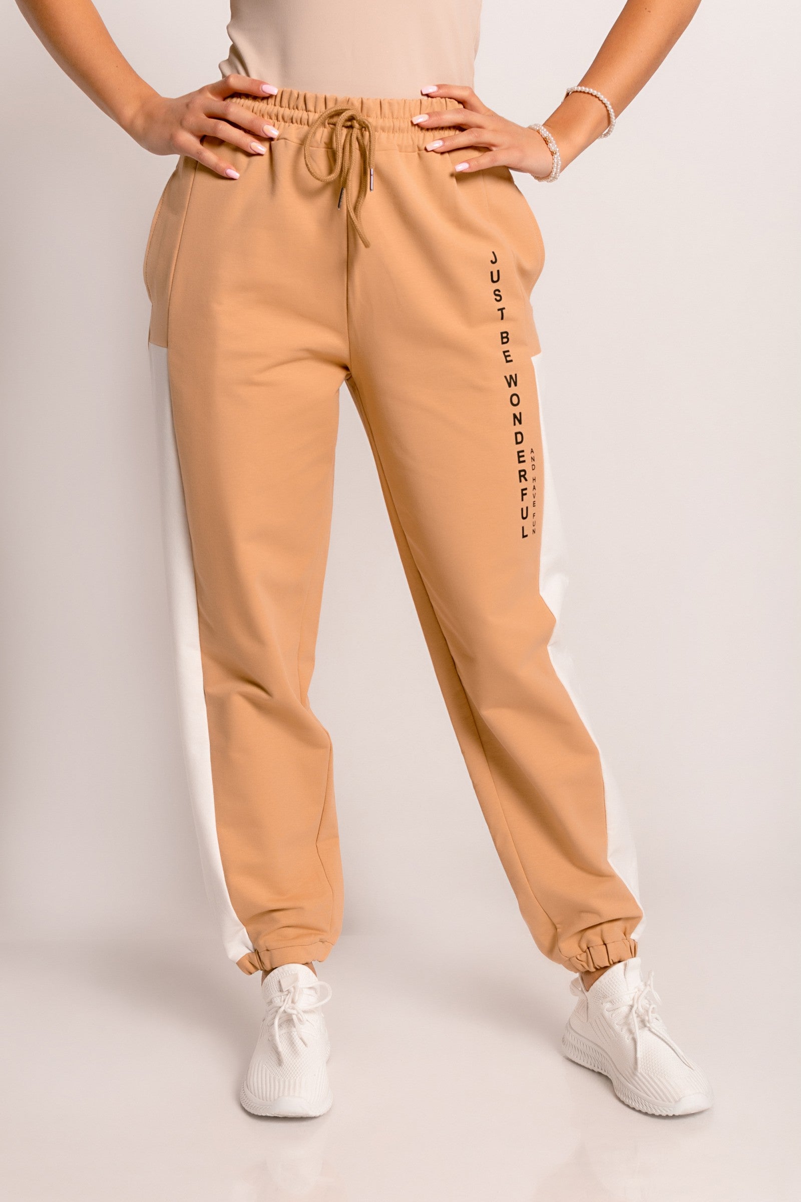 Beige cotton trousers with a decorative print, featuring an elastic waistband and ankle cuffs, perfect for sports and leisure.