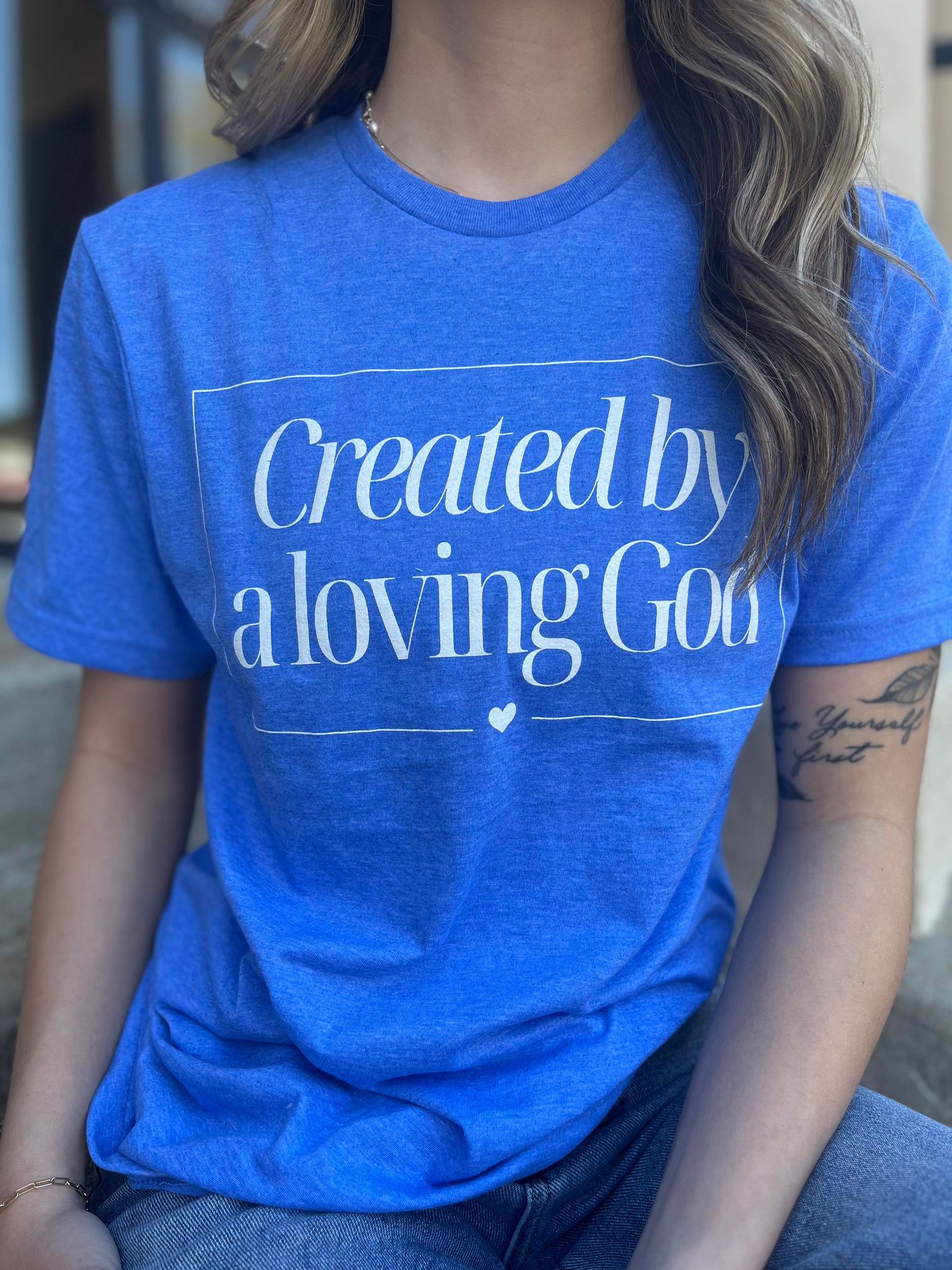 A stylish Heather Royal tee with the phrase 'Created by A Loving God' printed on it, showcasing a comfortable fit.