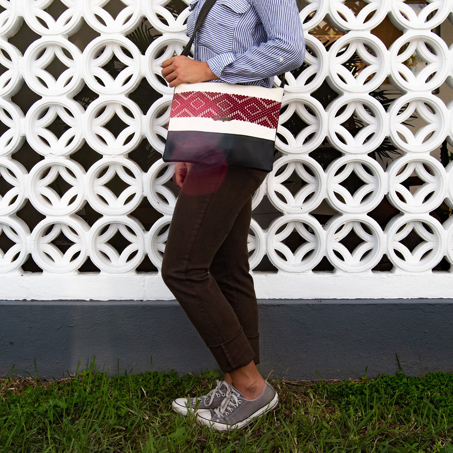 Elegant black leather cross-body bag featuring a burgundy stripe and geometric woven design, perfect for everyday use.