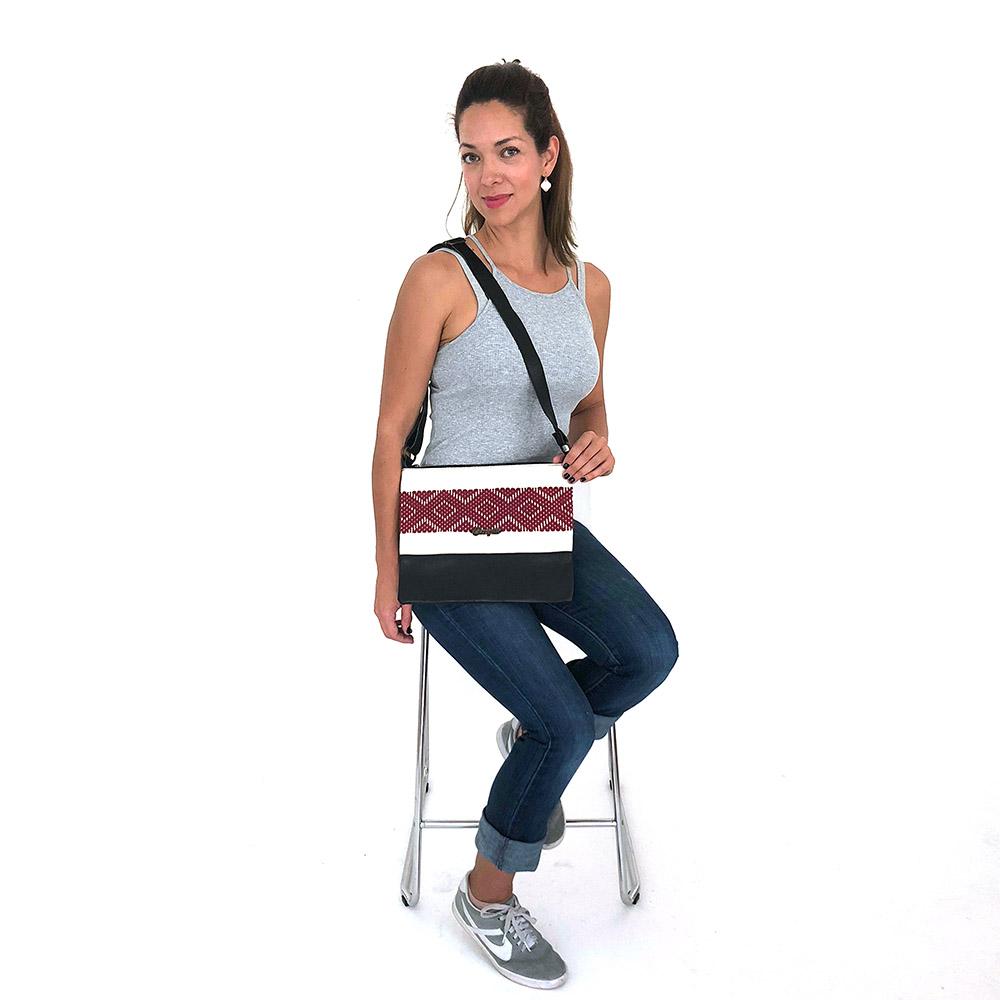Elegant black leather cross-body bag featuring a burgundy stripe and geometric woven design, perfect for everyday use.