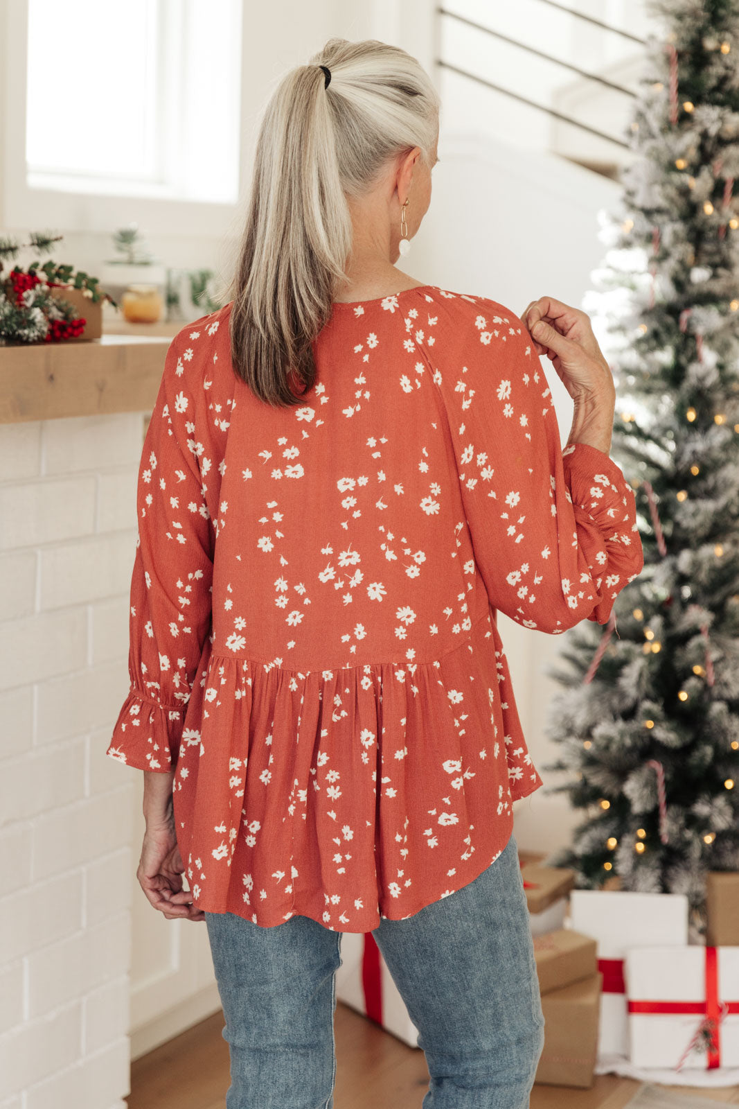 Daisy Flow Blouse in Rust featuring a lightweight, flowy design with a babydoll silhouette, tie-up collar, and cinched sleeves.