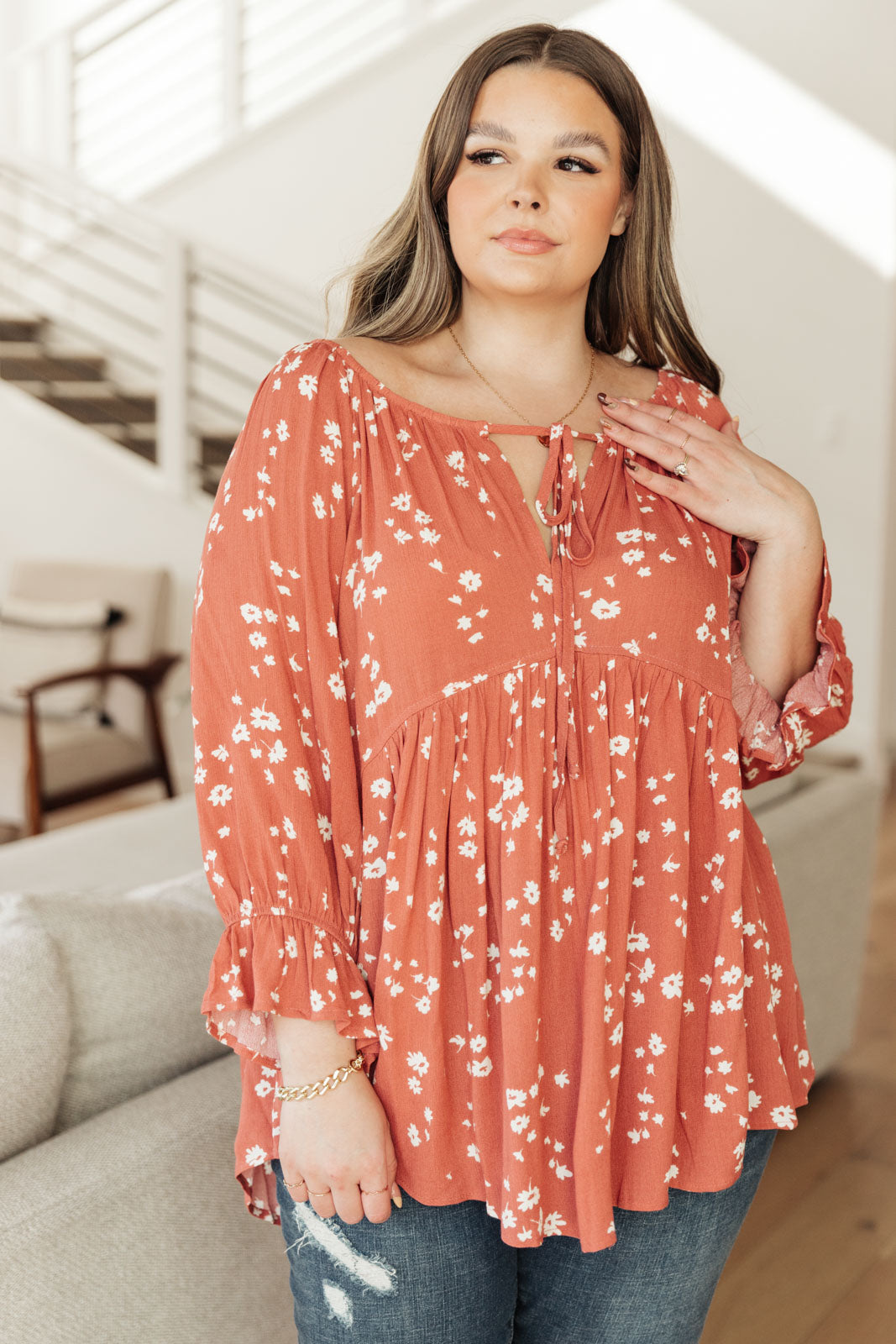 Daisy Flow Blouse in Rust featuring a lightweight, flowy design with a babydoll silhouette, tie-up collar, and cinched sleeves.