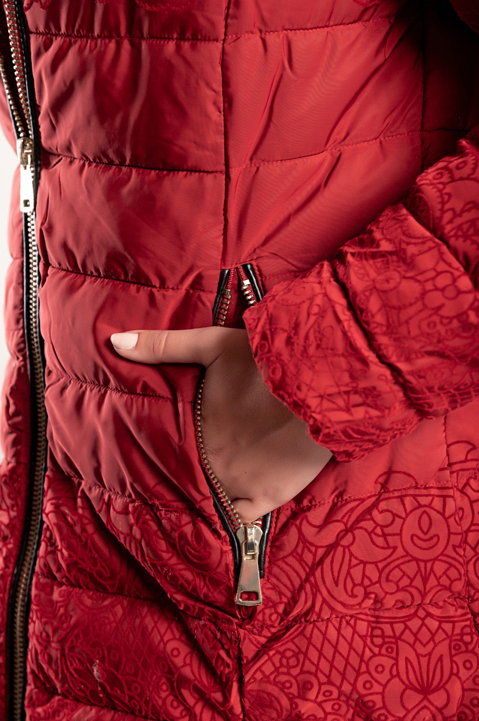 Dolga prešita bunda Elcha v rdeči barvi z modrim vzorcem iz imitacije žameta, visokim ovratnikom in stranskima žepoma z zadrgo.