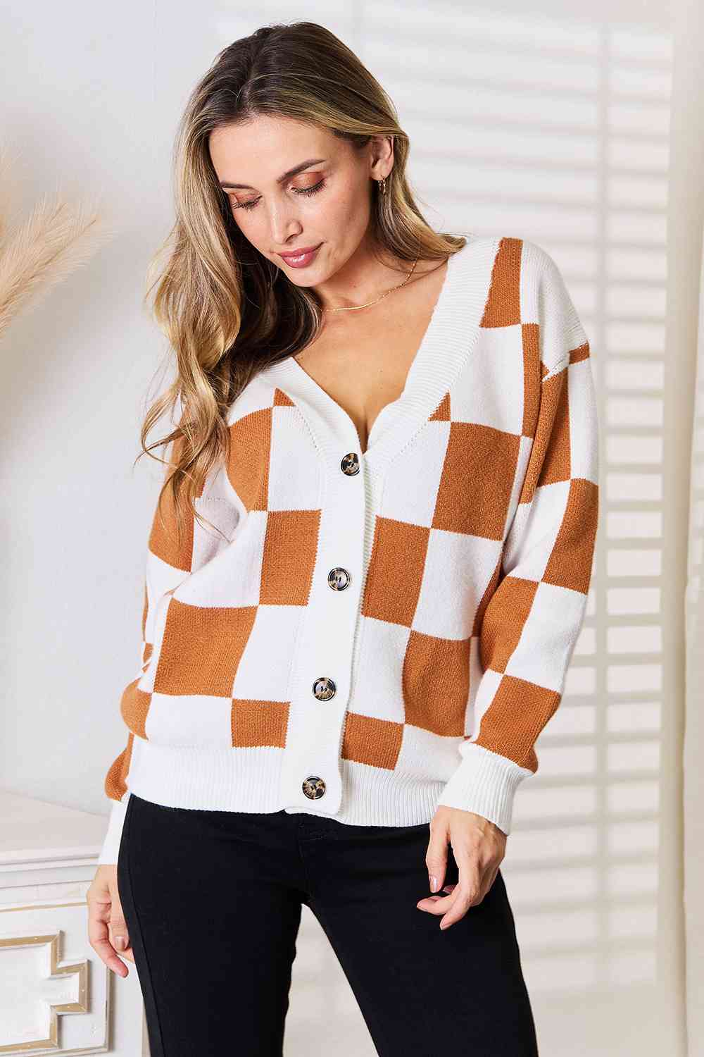 A stylish checkered button-up V-neck cardigan with dropped shoulders, showcasing its trendy design and cozy fit.