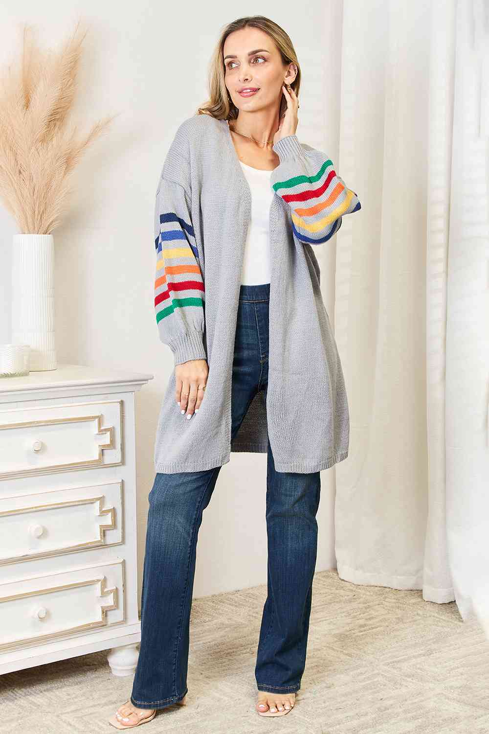 A vibrant multicolored stripe open front longline cardigan displayed on a mannequin, showcasing its stylish design and long silhouette.