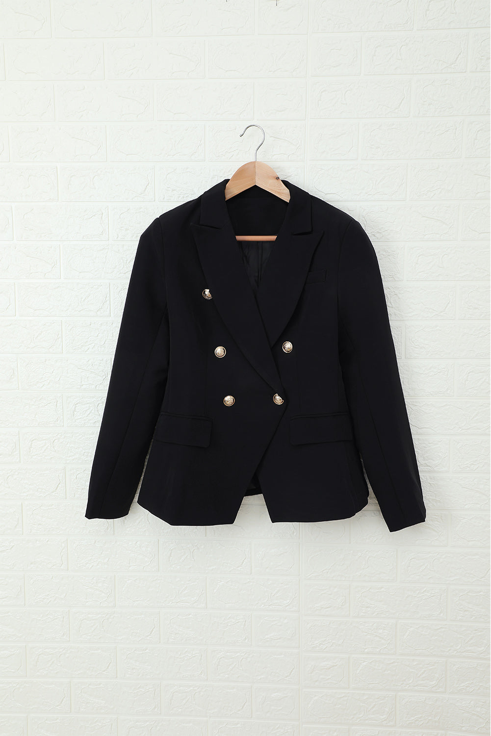 Double-breasted lapel collar blazer in solid color with pockets, displayed flat lay outdoors on a hanger.