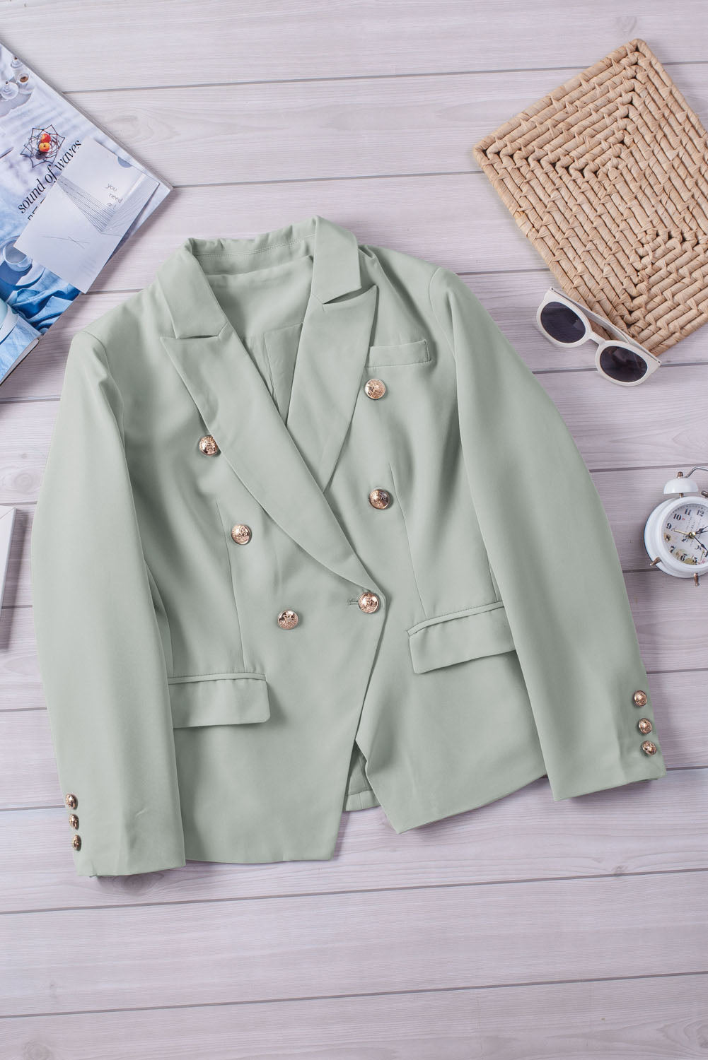 Double-breasted lapel collar blazer in solid color with pockets, displayed flat lay outdoors on a hanger.