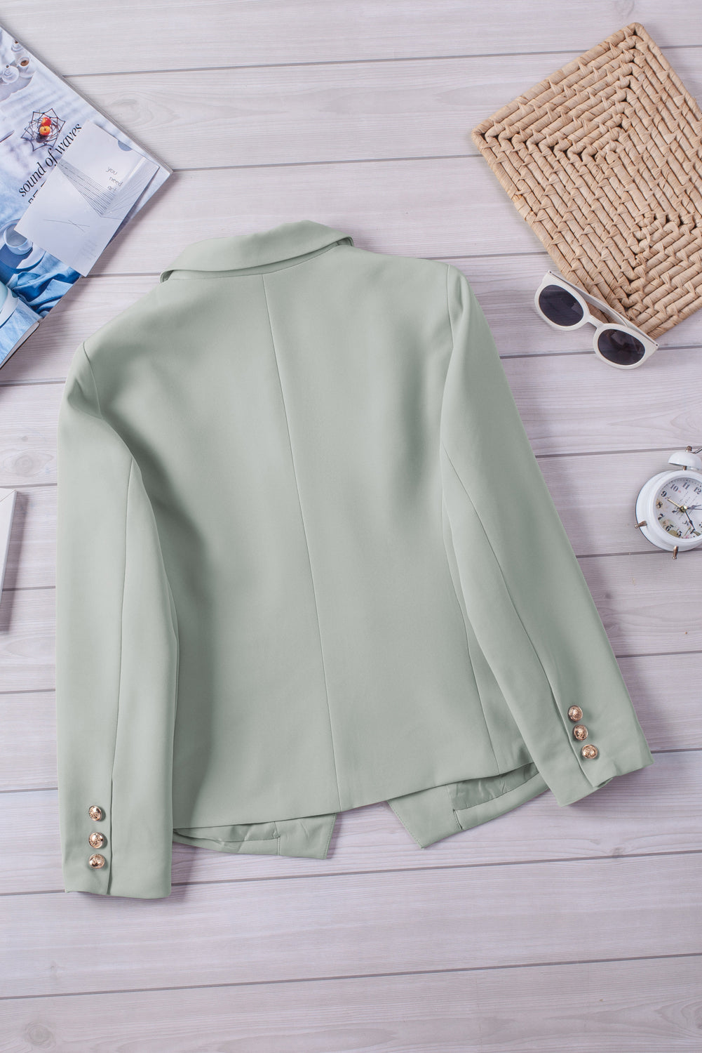 Double-breasted lapel collar blazer in solid color with pockets, displayed flat lay outdoors on a hanger.