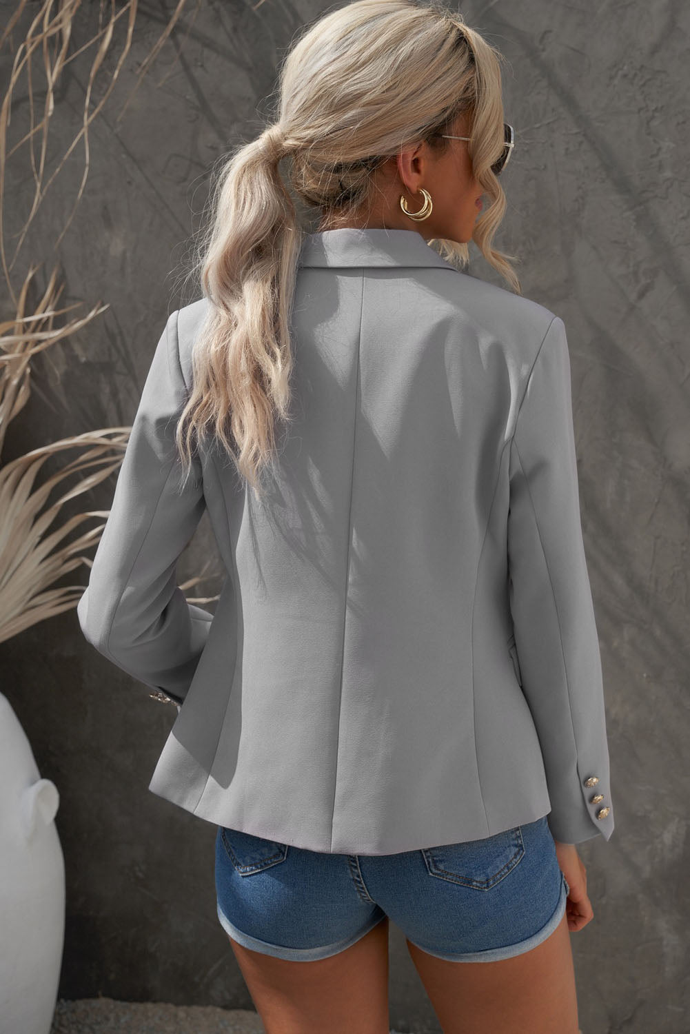Double-breasted lapel collar blazer in solid color with pockets, displayed flat lay outdoors on a hanger.