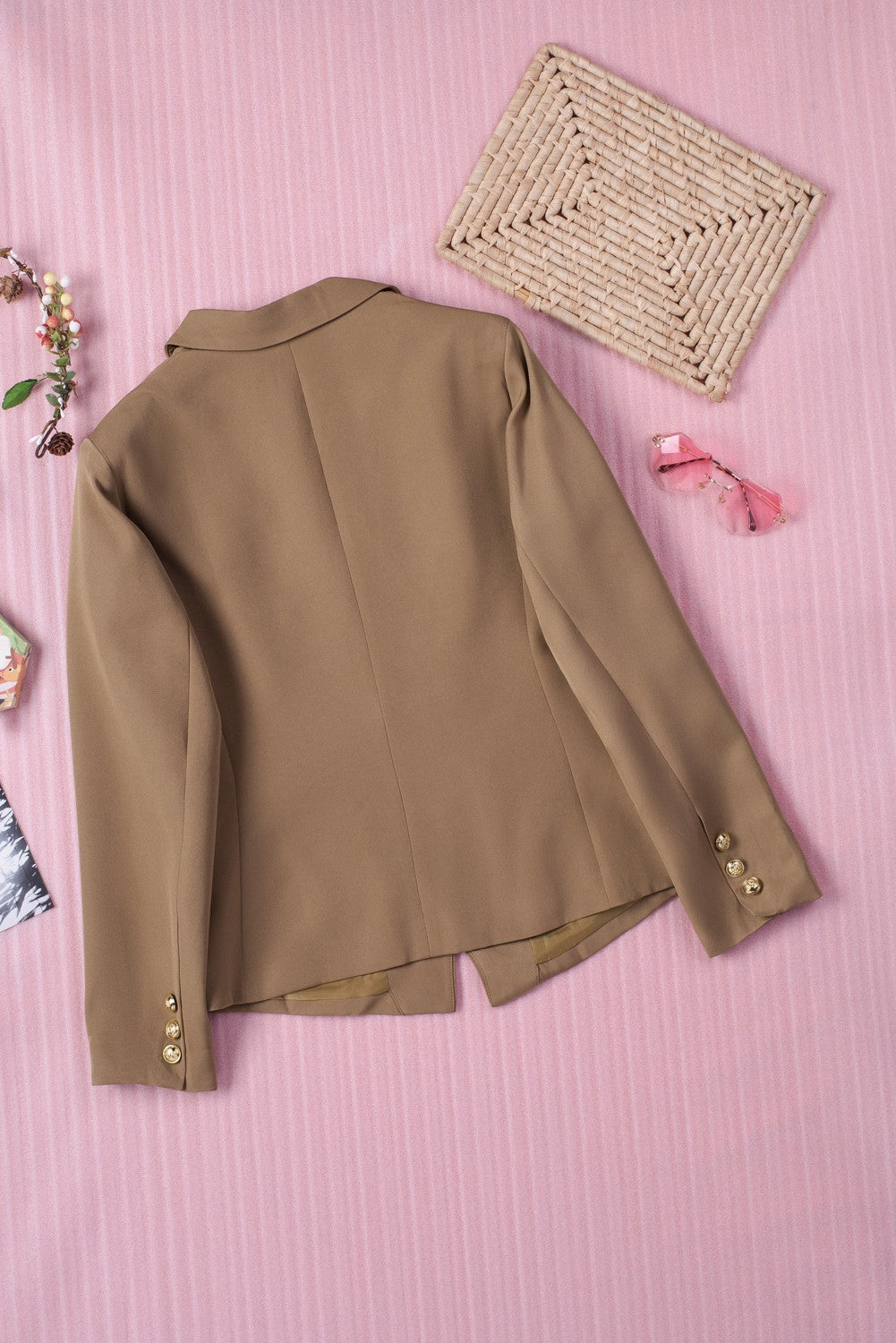 Double-breasted lapel collar blazer in solid color with pockets, displayed flat lay outdoors on a hanger.