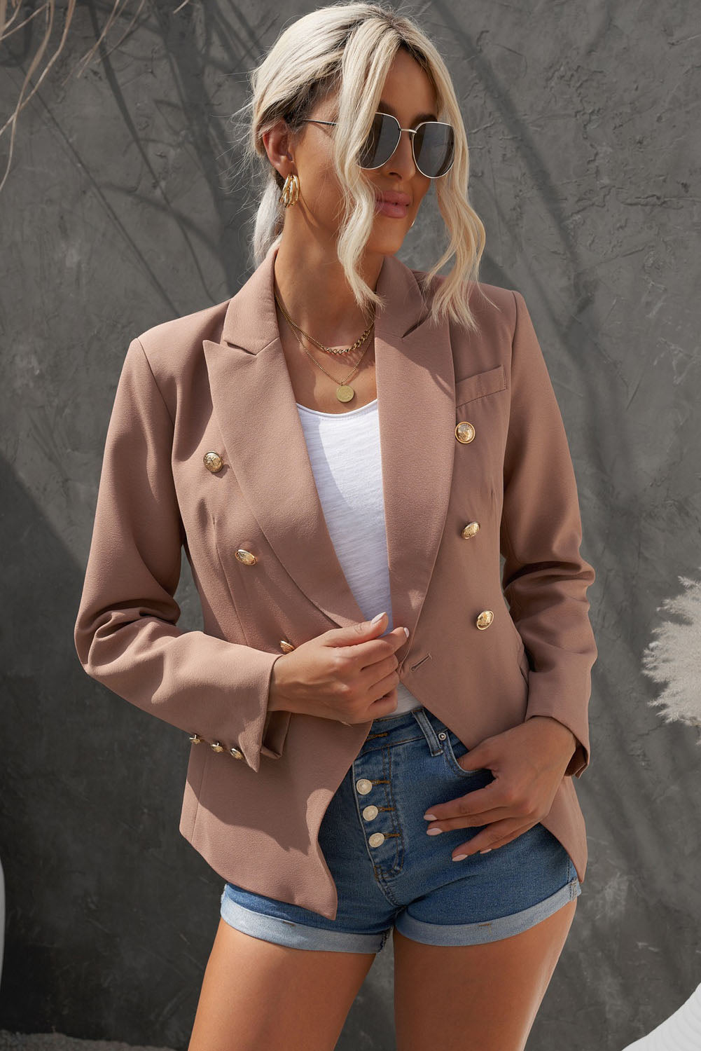 Double-breasted lapel collar blazer in solid color with pockets, displayed flat lay outdoors on a hanger.