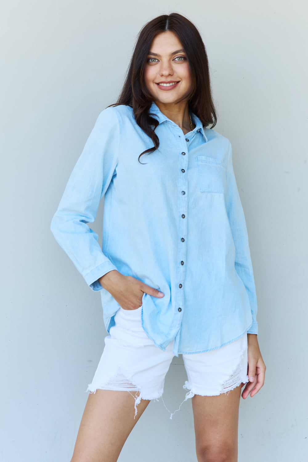 Light blue denim button down shirt with pointed collar and buttoned cuffs, showcasing a casual yet chic style.