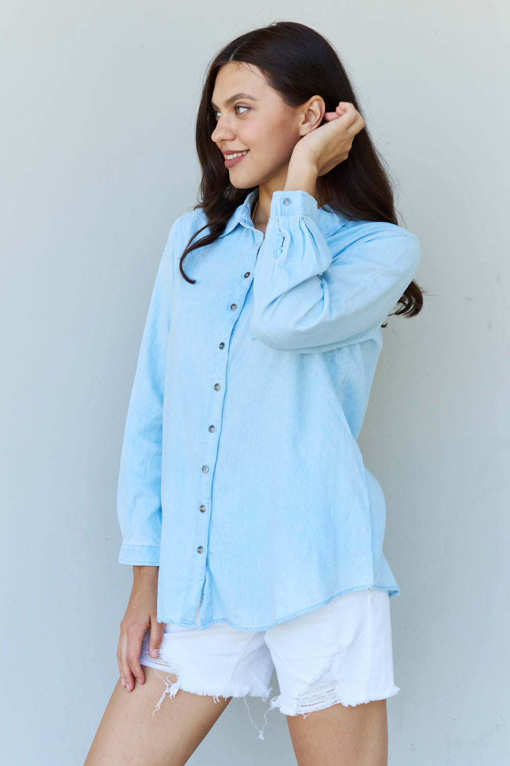 Light blue denim button down shirt with pointed collar and buttoned cuffs, showcasing a casual yet chic style.