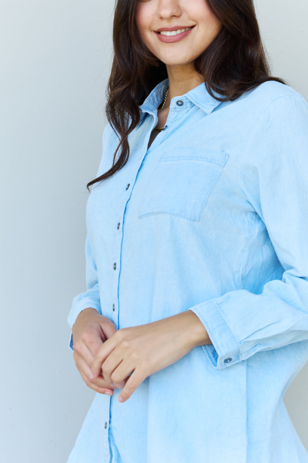 Light blue denim button down shirt with pointed collar and buttoned cuffs, showcasing a casual yet chic style.