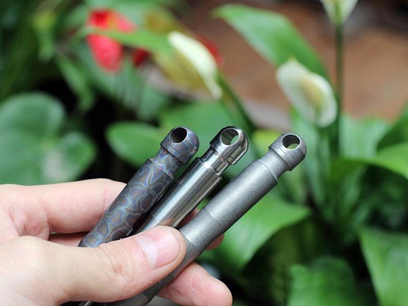 EDC Outdoor Titanium TC4 Krait Tactical Pen in three finishes: Natural, Stone Wash, and Flame, showcasing its sleek design and compact size.