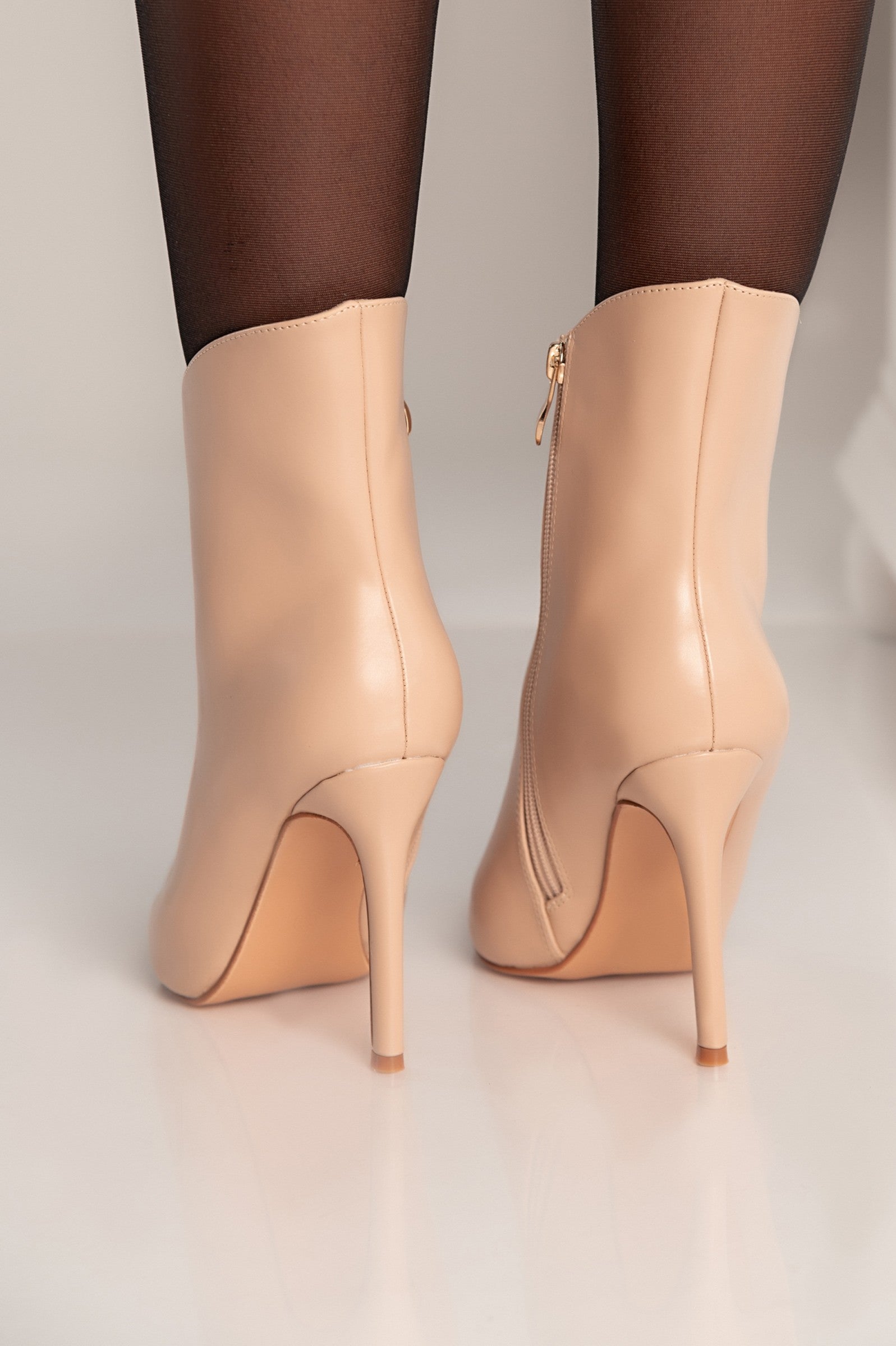 Elegant beige ankle boots with high heels and pointed toe design, featuring an inside zip closure.