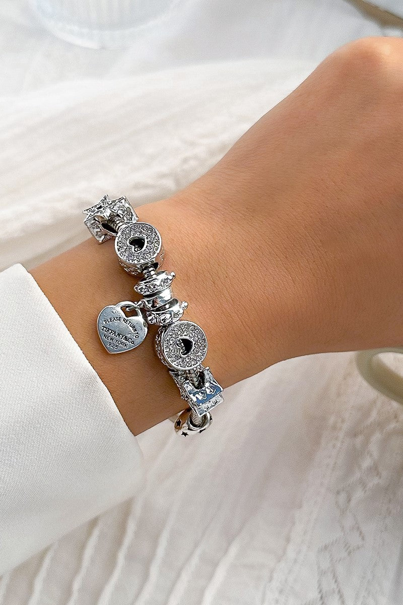 Elegant silver bracelet adorned with decorative pendants and stones, featuring a secure metal hook closure.