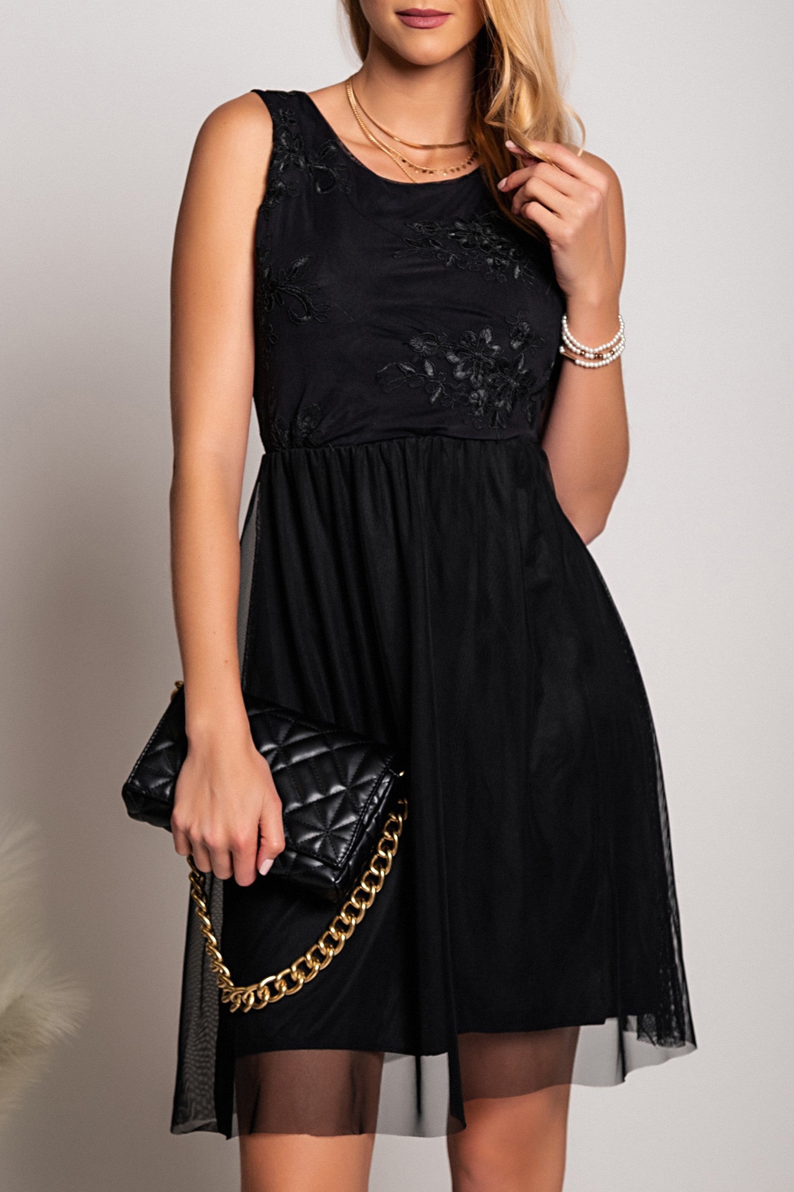 Elegant black dress with round neckline and intricate embroidery detail, featuring wide straps and a knee-length two-layered skirt.
