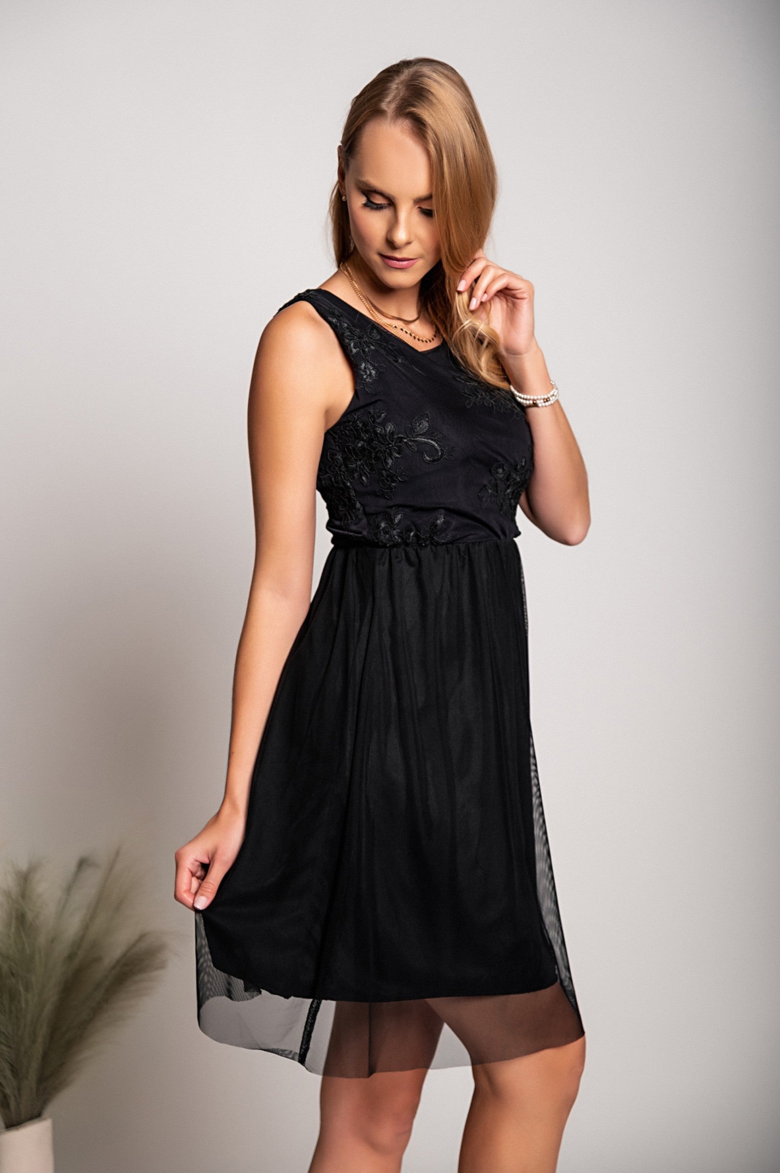 Elegant black dress with round neckline and intricate embroidery detail, featuring wide straps and a knee-length two-layered skirt.