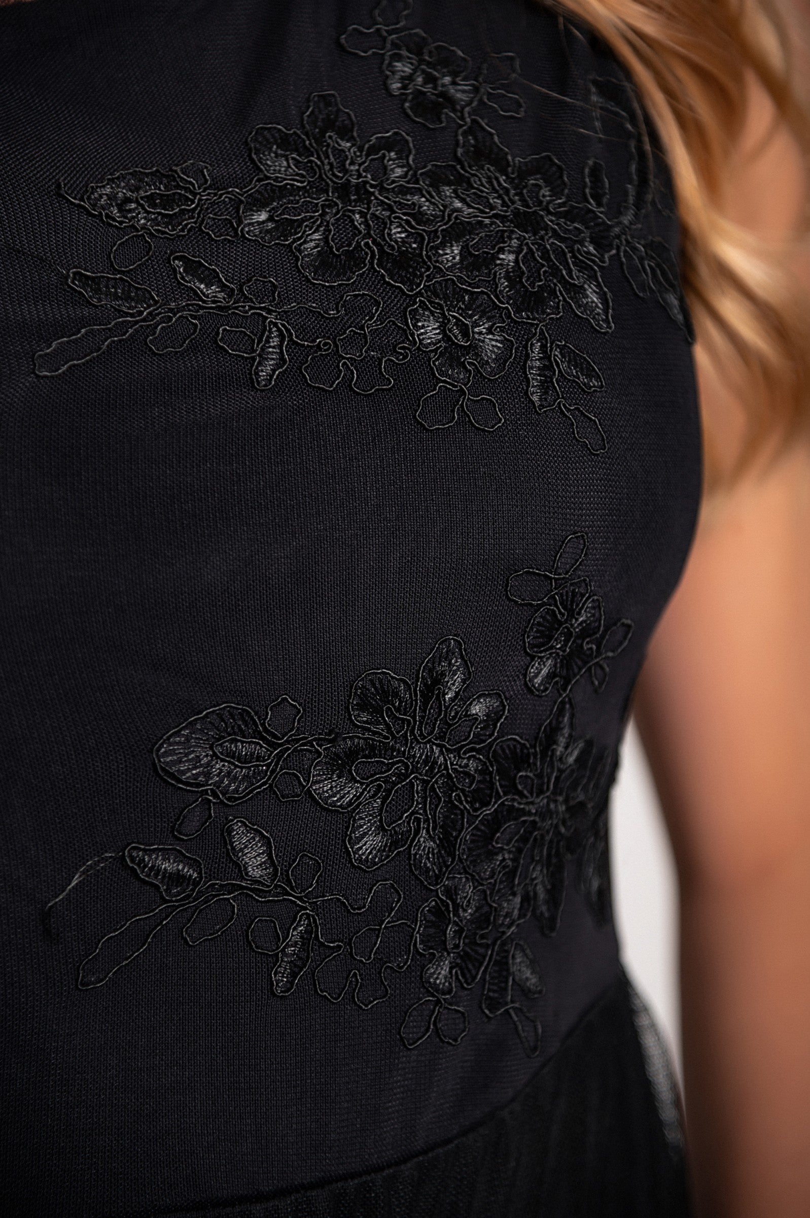 Elegant black dress with round neckline and intricate embroidery detail, featuring wide straps and a knee-length two-layered skirt.