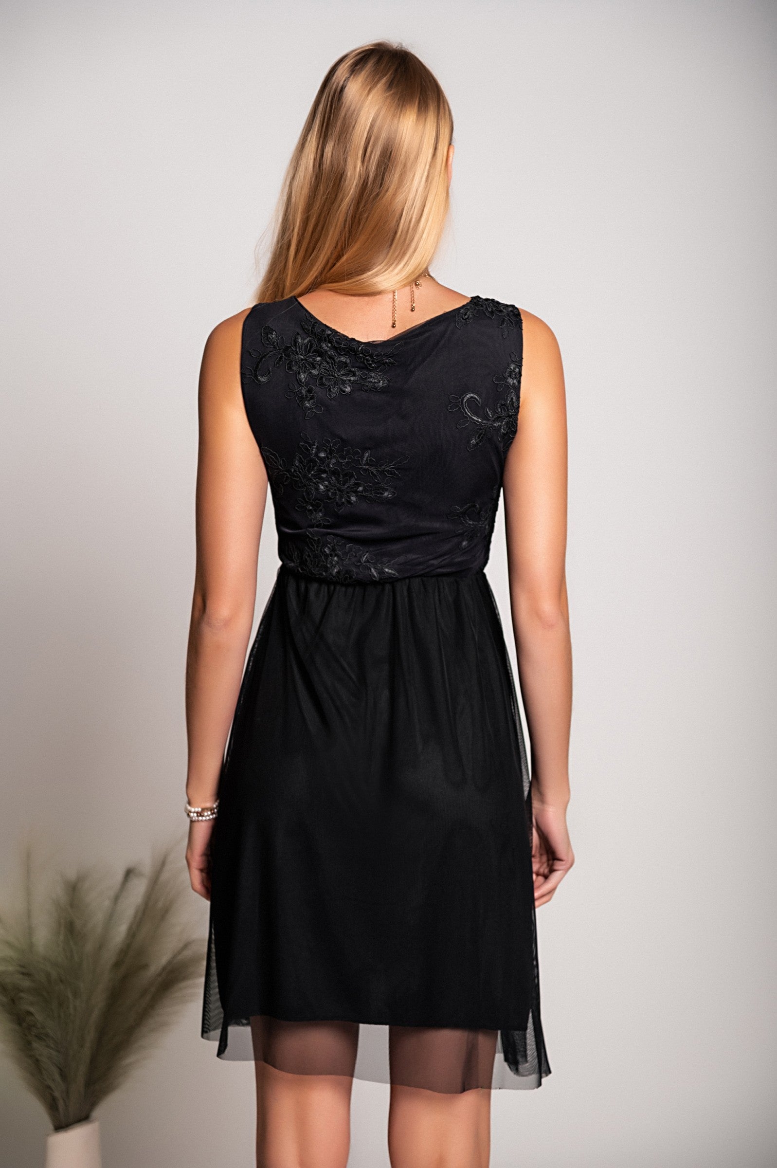Elegant black dress with round neckline and intricate embroidery detail, featuring wide straps and a knee-length two-layered skirt.