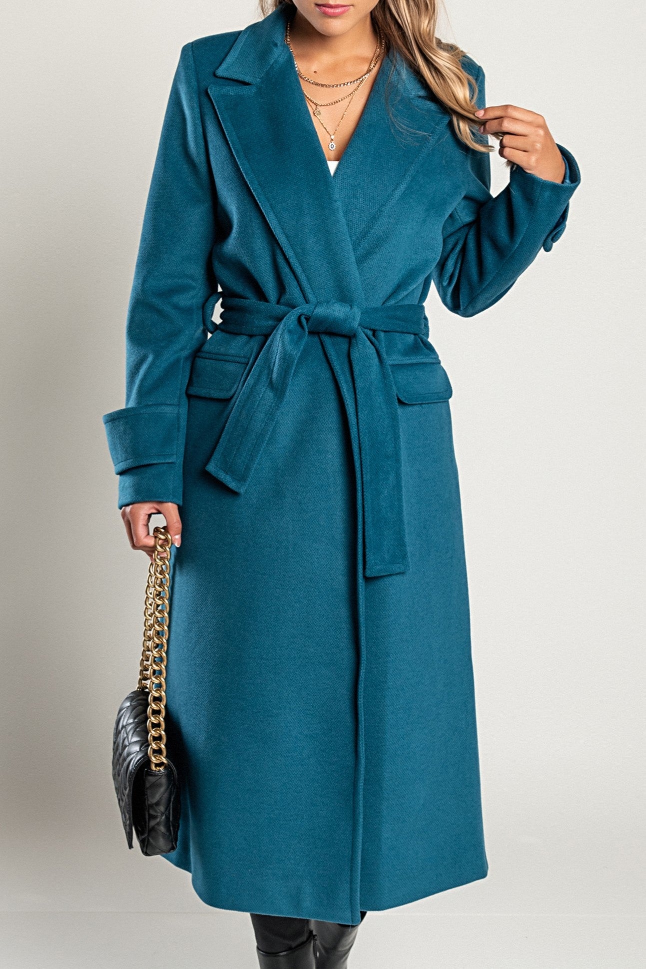 Elegant long coat Canossa in petrol color, featuring a classic collar and decorative belt, made from soft and warm fabric.
