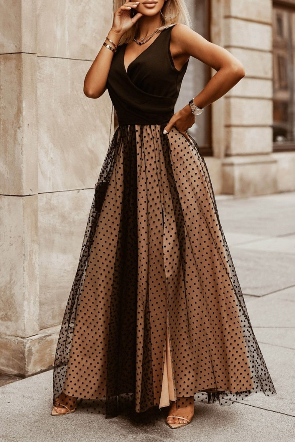 Elegant black maxi dress with polka dots featuring a deep neckline and wide straps, complemented by a transparent tulle overlay skirt.