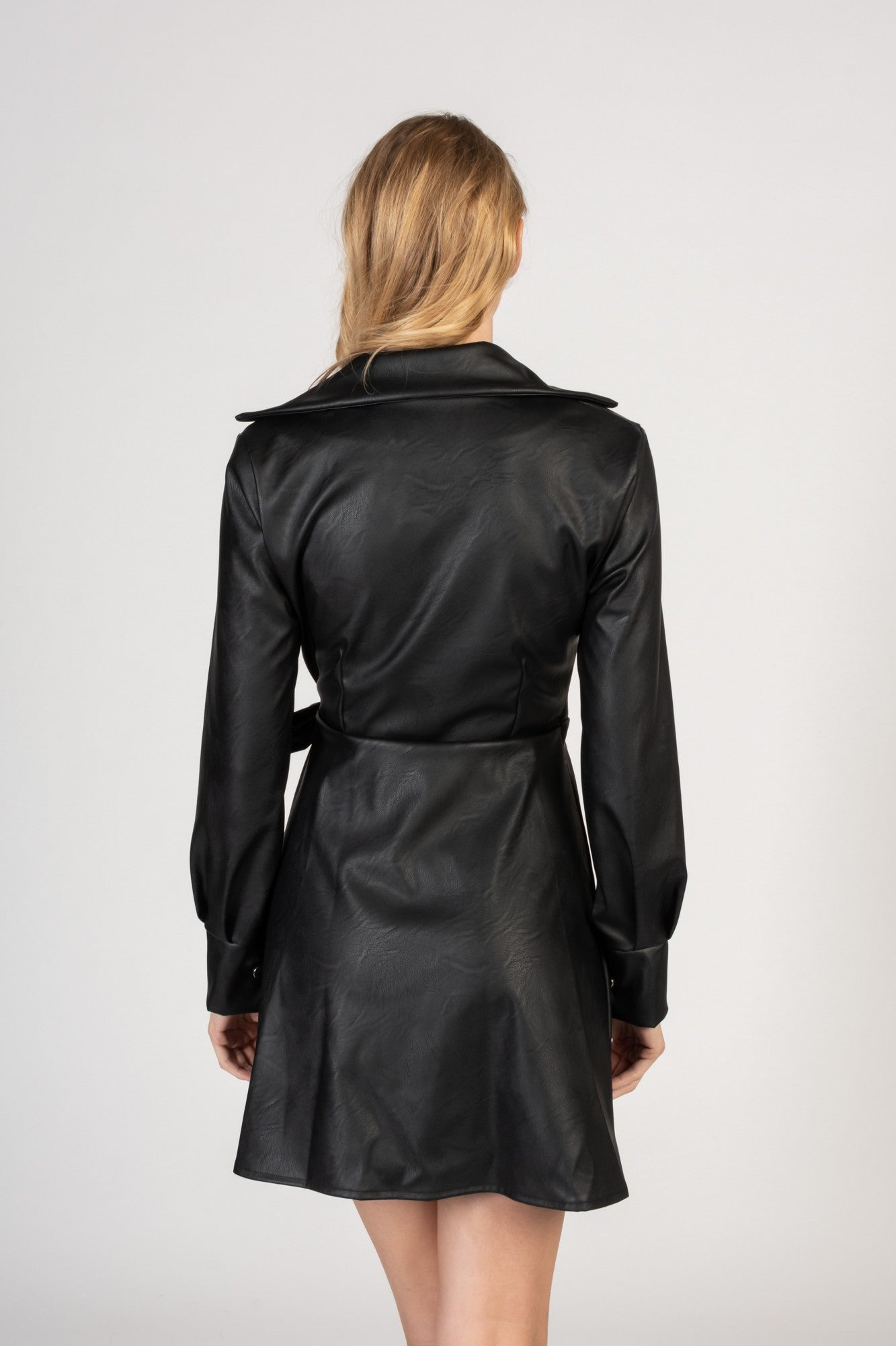 Elegant black mini dress made of faux leather with a folding collar and long sleeves, featuring a tied waist and knee-length skirt.