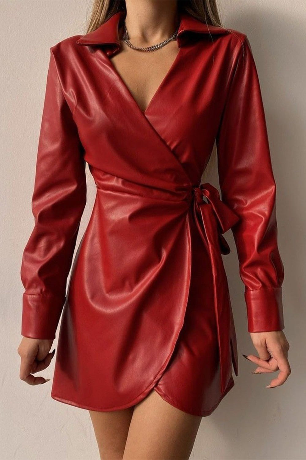 Elegant red mini dress made of high-quality faux leather with a folding collar and long sleeves, featuring a tied waist and knee-length skirt.