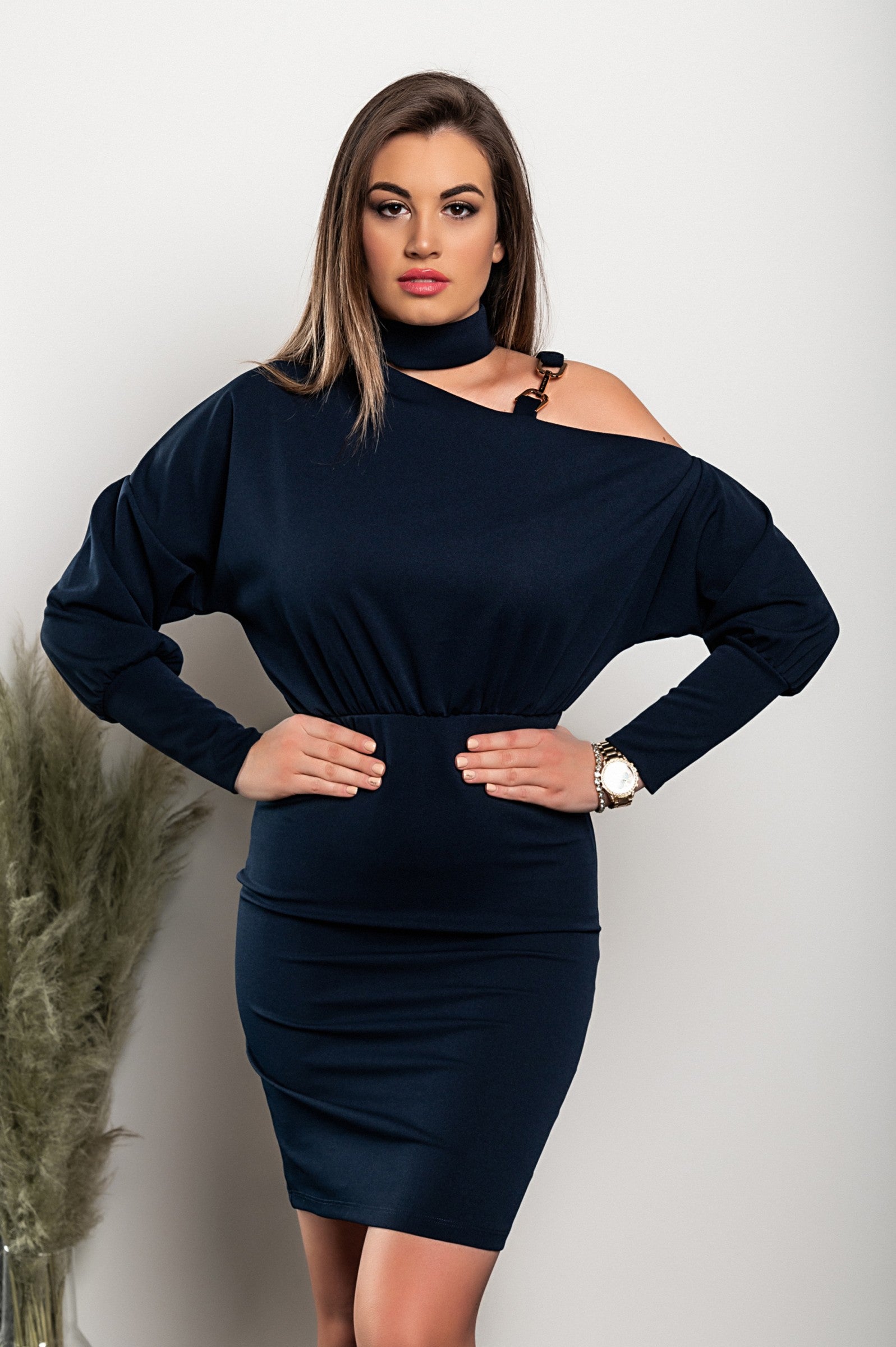Elegant dark blue mini dress with asymmetrical neckline and decorative chain, showcasing a fitted mid-thigh skirt and long sleeves.