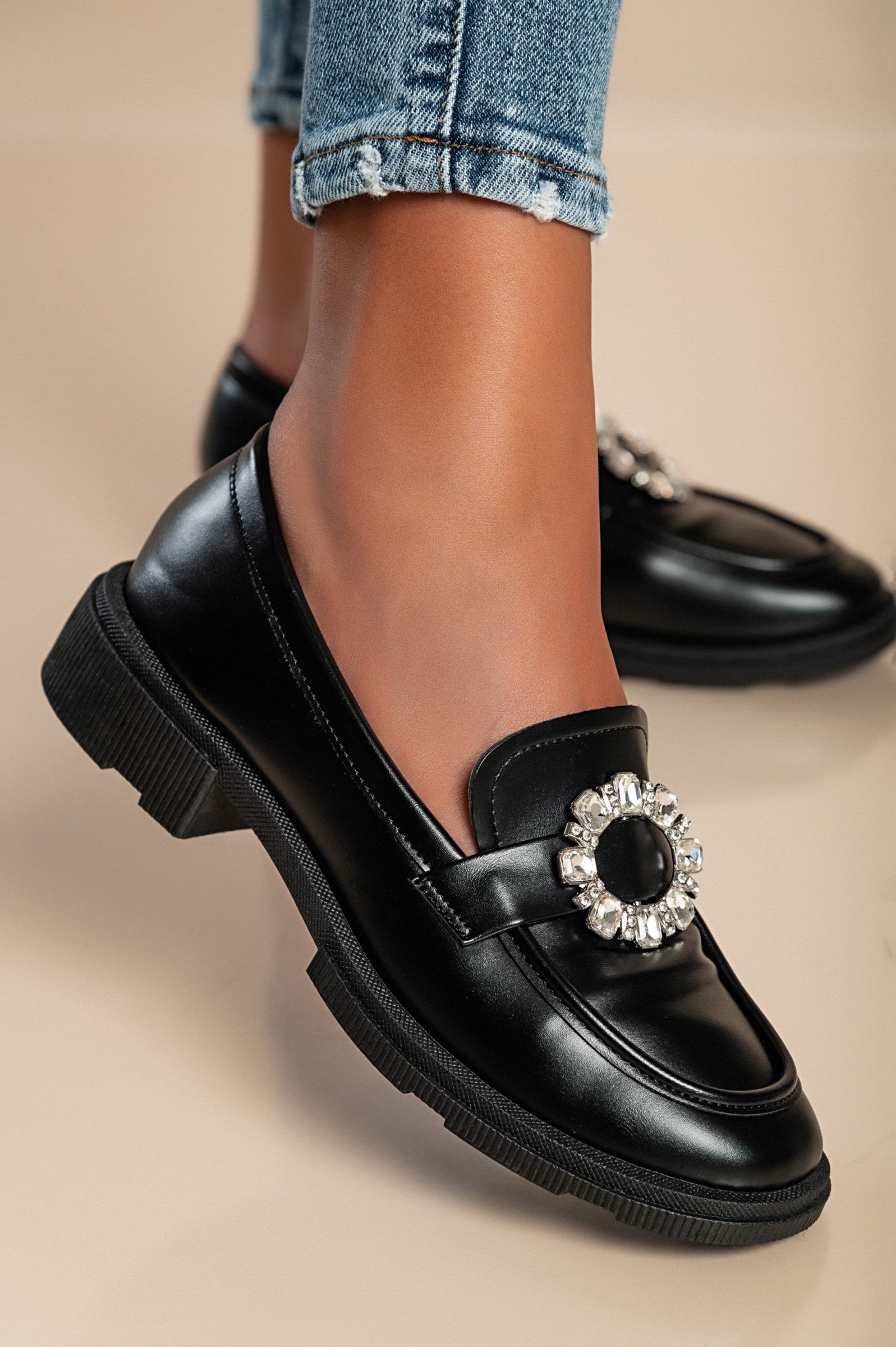 Elegant black moccasins with flat sole and decorative detail, showcasing quality craftsmanship and stylish design.