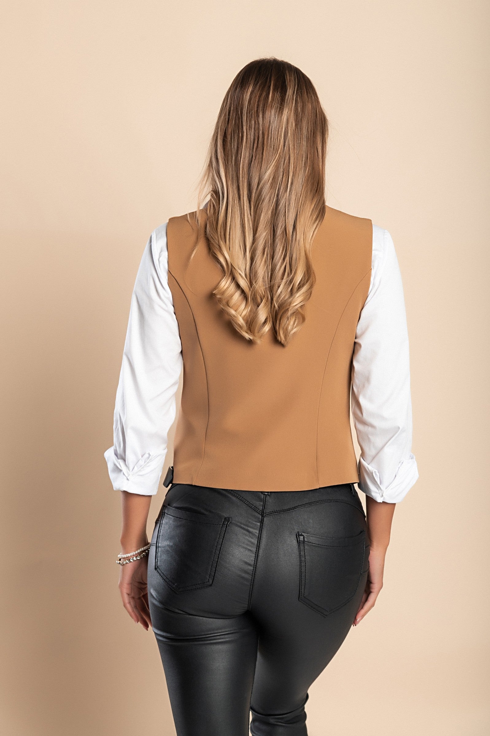 Elegant camel color vest with buttons, featuring a V-neckline and decorative side pockets, fully lined for comfort.