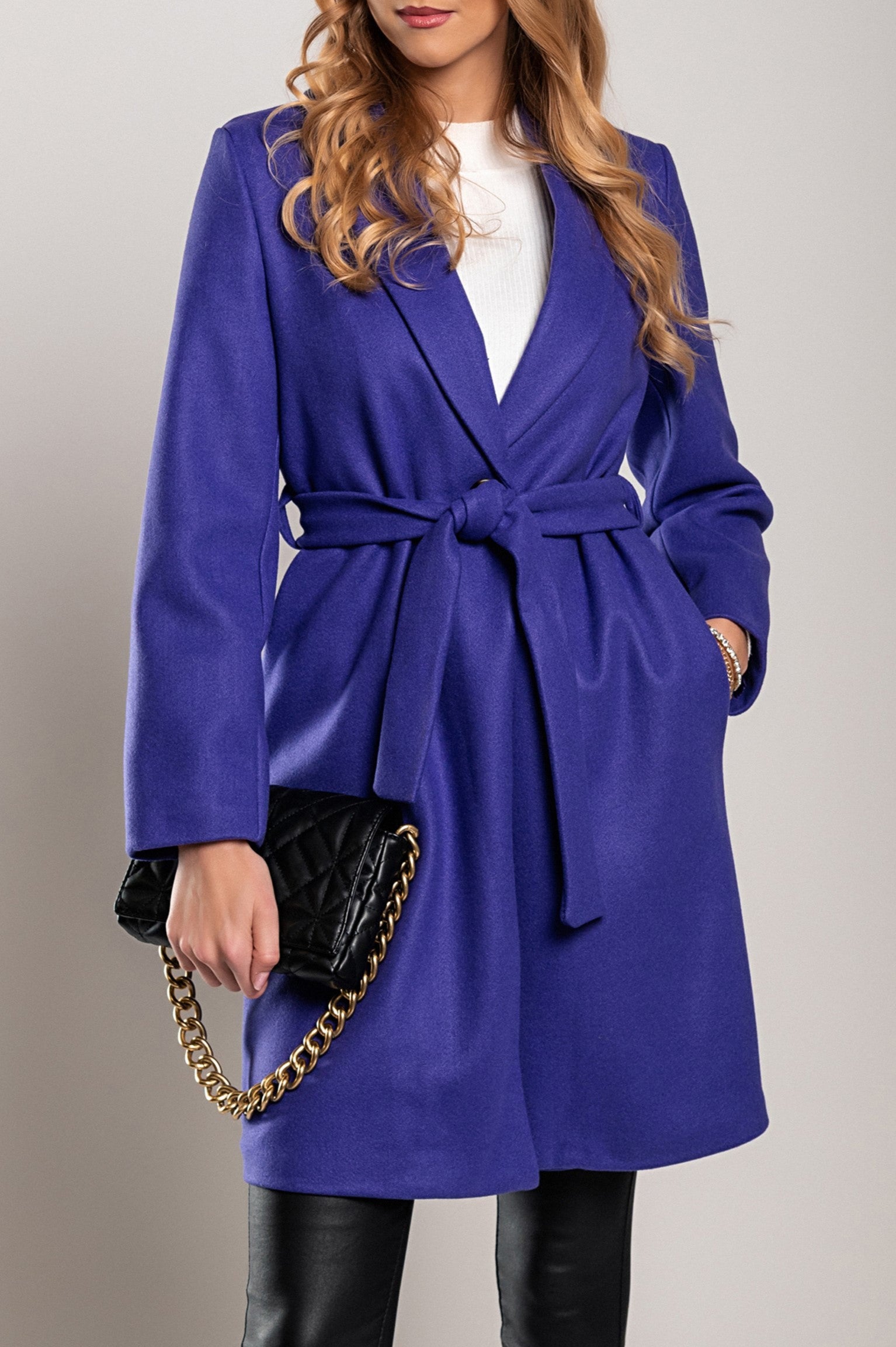 Eleganten daljši plašč z ovratnikom v vijolični barvi, izdelan iz mehkega poliestra, z dolgimi rokavi in okrasnim pasom.