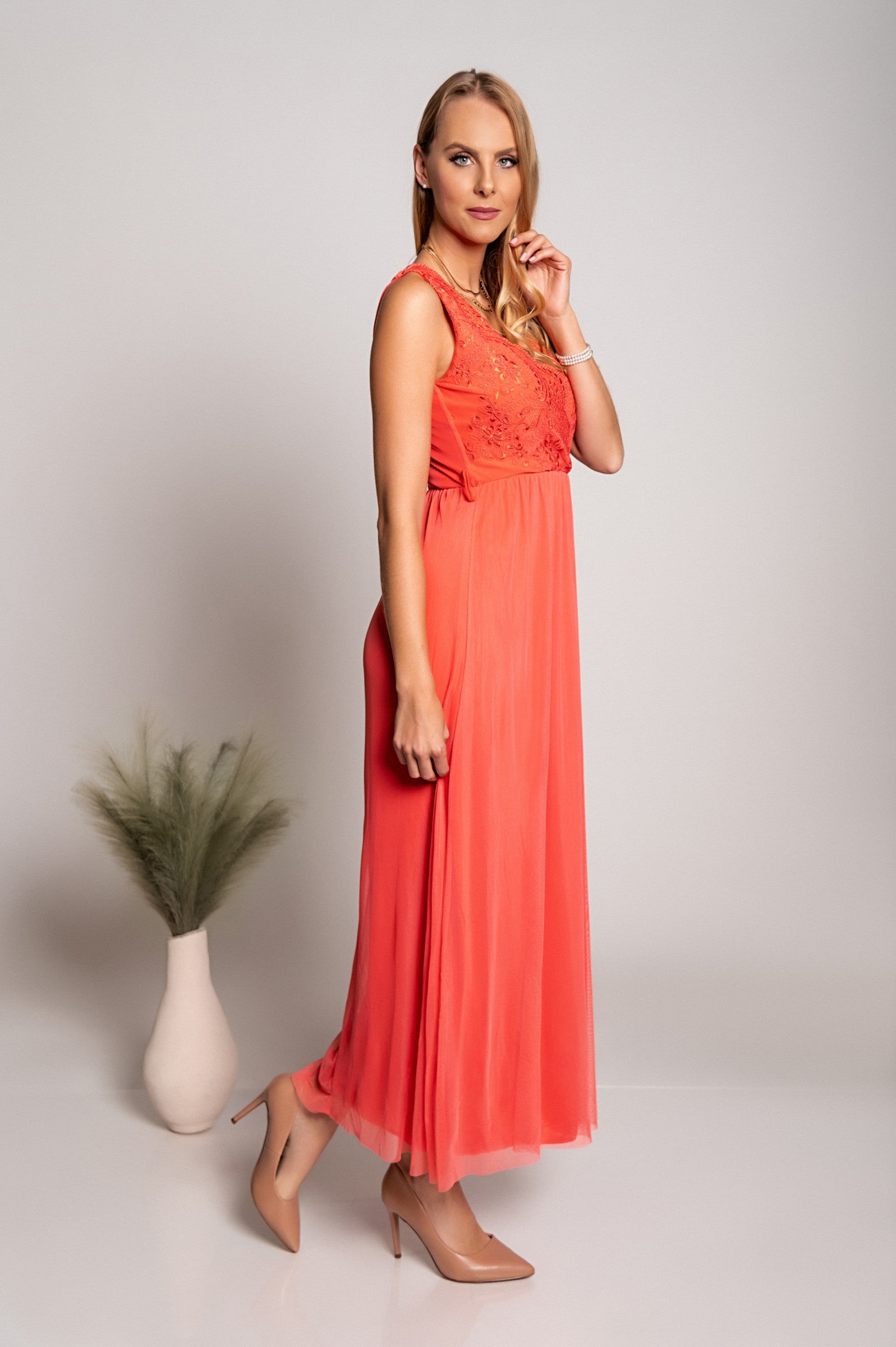 Elegantna dolga obleka z 'V' izrezom in detajlom vezenine, izdelana iz mehkega in elastičnega blaga.